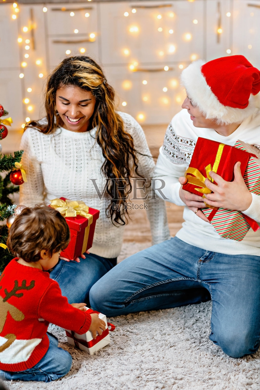 给所有家庭成员的圣诞礼物。父母带着孩子在新家的圣诞树前。照片摄影图片