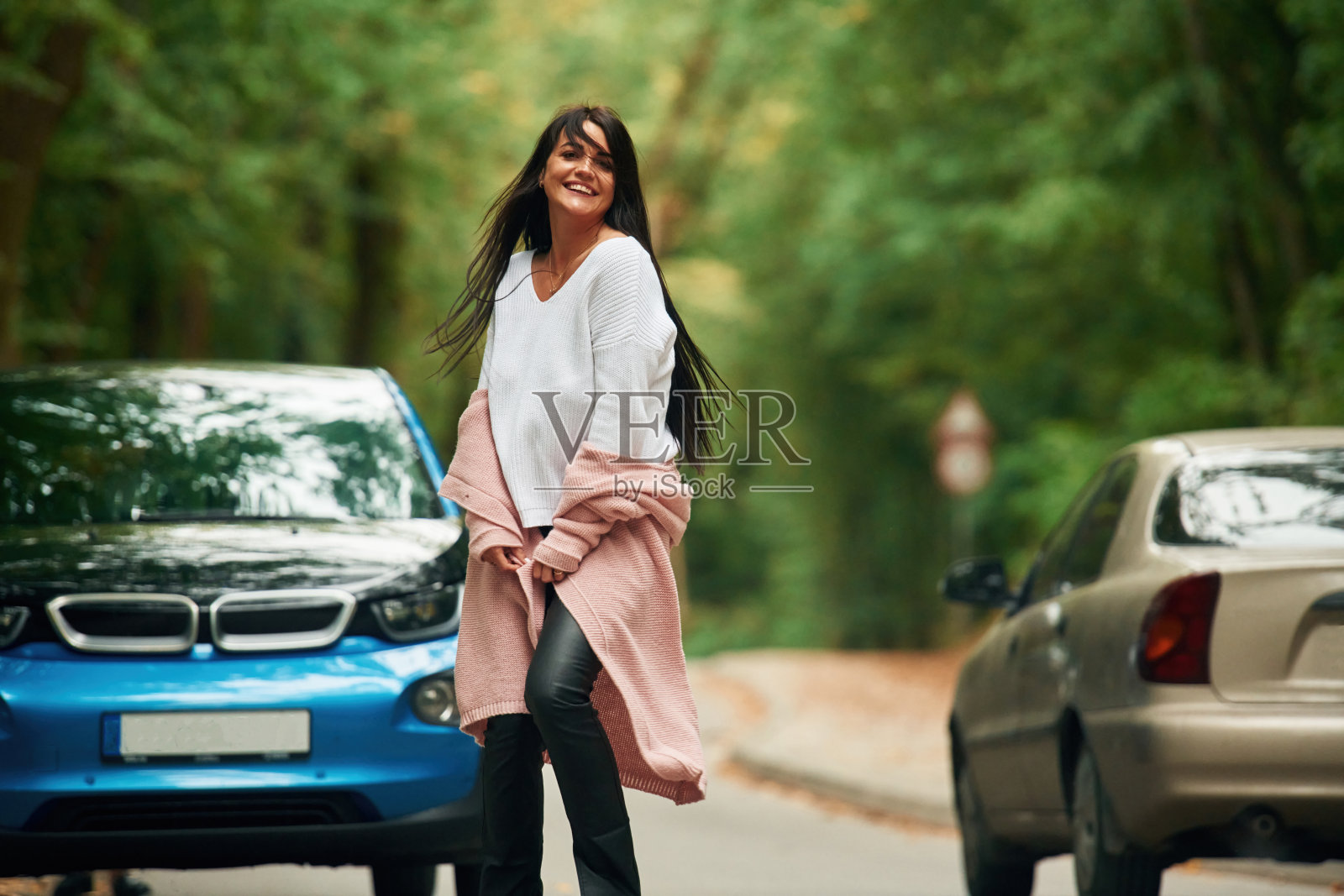 开朗美丽的女人在户外靠近一辆蓝色的汽车照片摄影图片