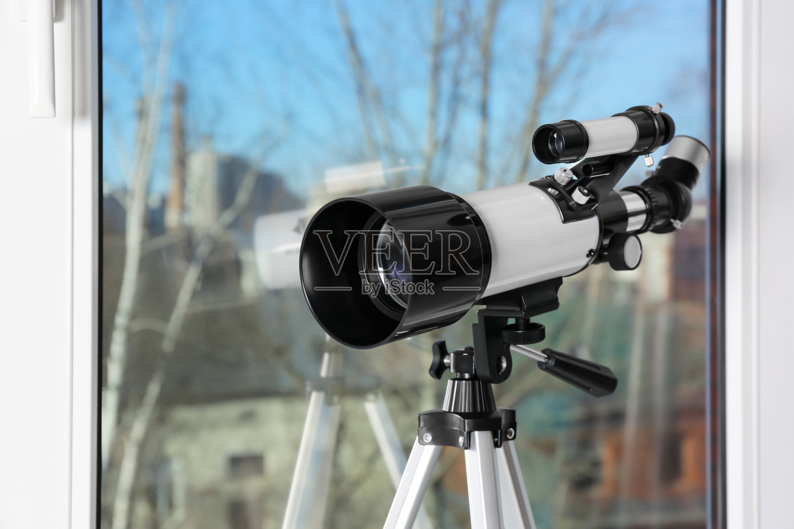 三脚架与现代望远镜靠近窗户，室内，特写照片摄影图片