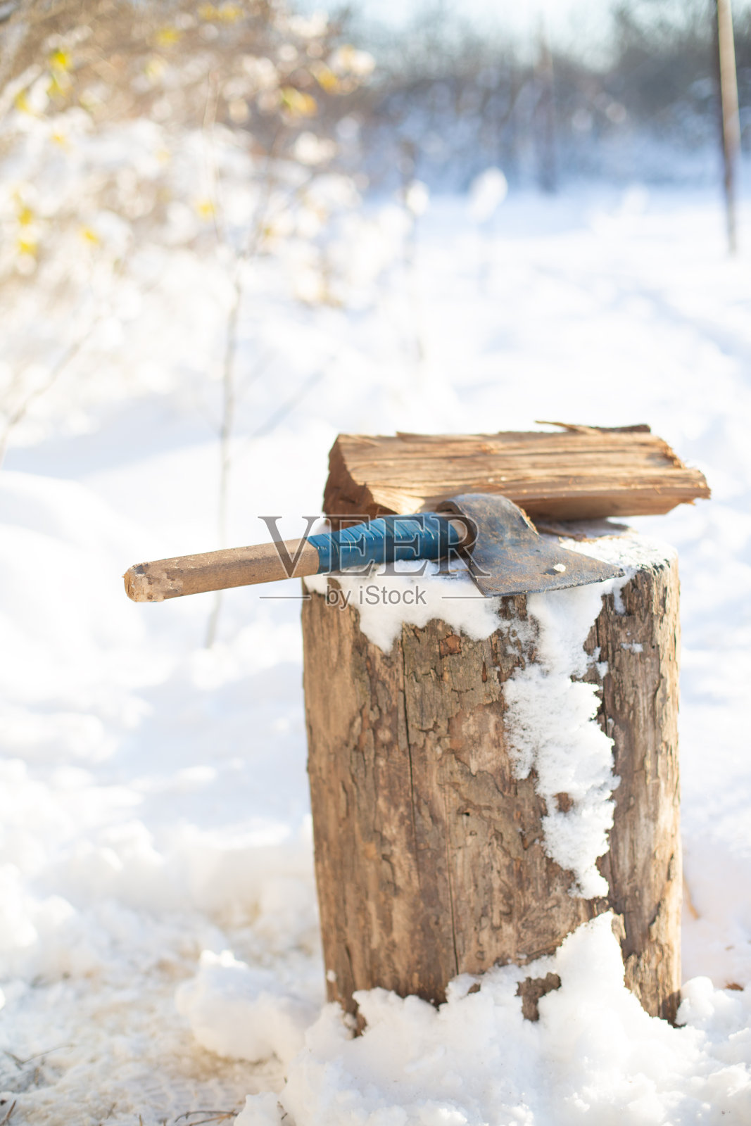 在冬天下雪的环境中，一个面目全非的人在砍柴照片摄影图片