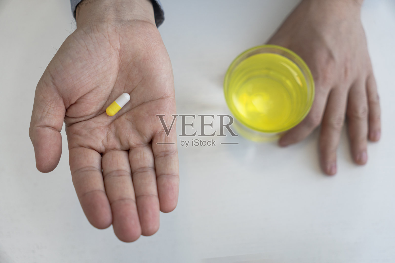 男性手里拿着白色和绿色药片的盘子和一杯白色背景的水。治疗的概念。前视图。照片摄影图片