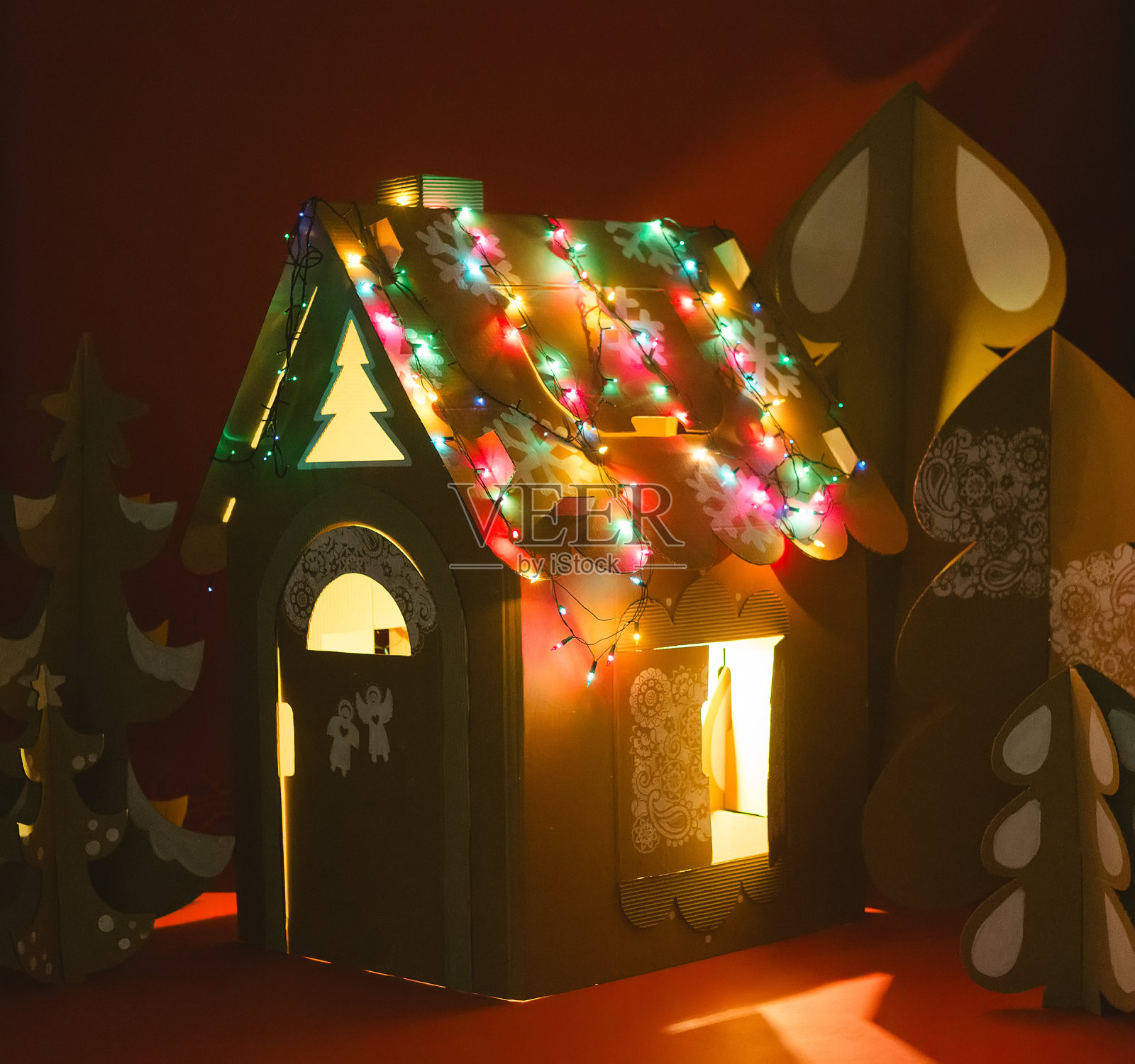 用硬纸板做成的圣诞树和玩具屋。独特的树木。新年或圣诞节。照片摄影图片