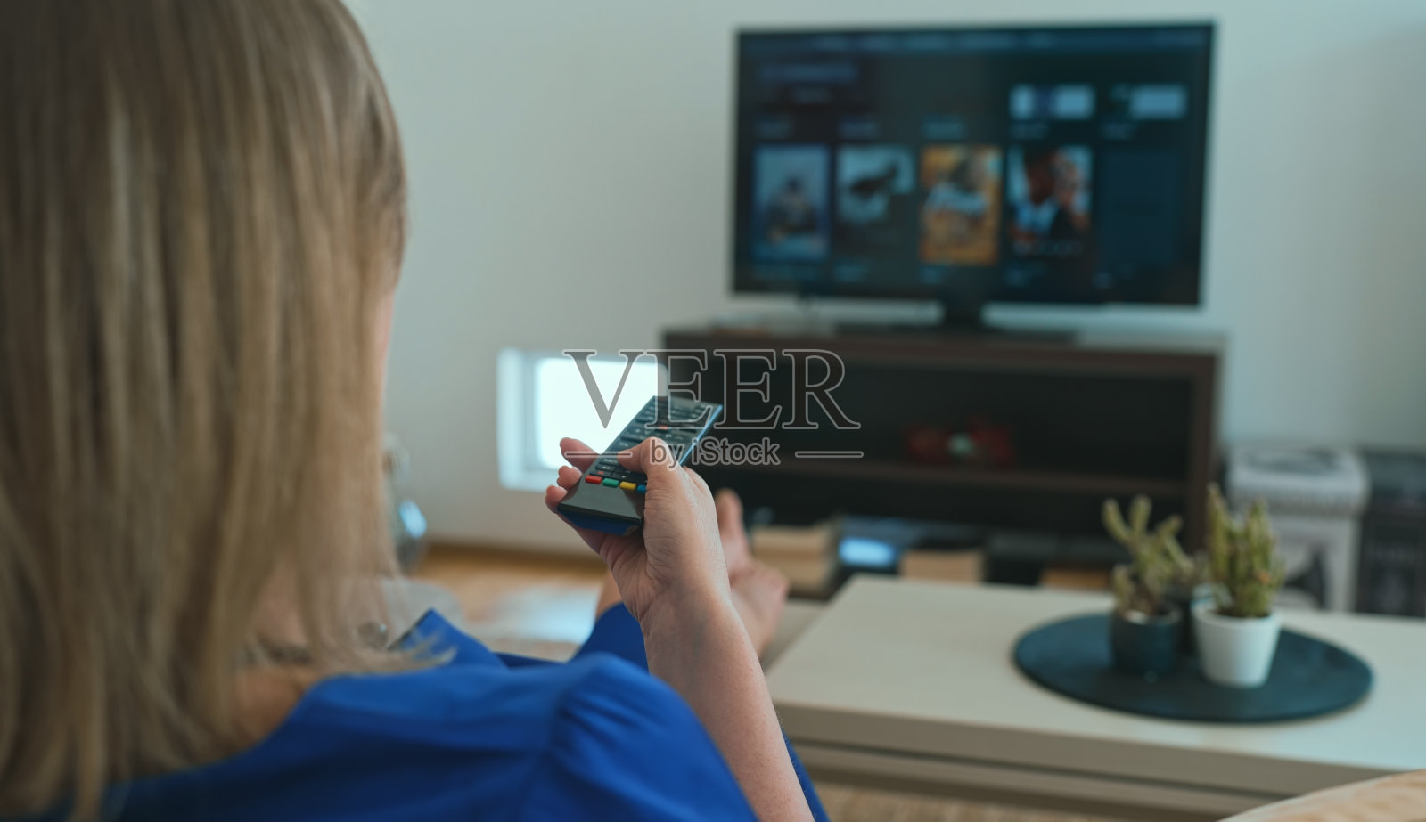 女人在家里用智能电视看节目。照片摄影图片