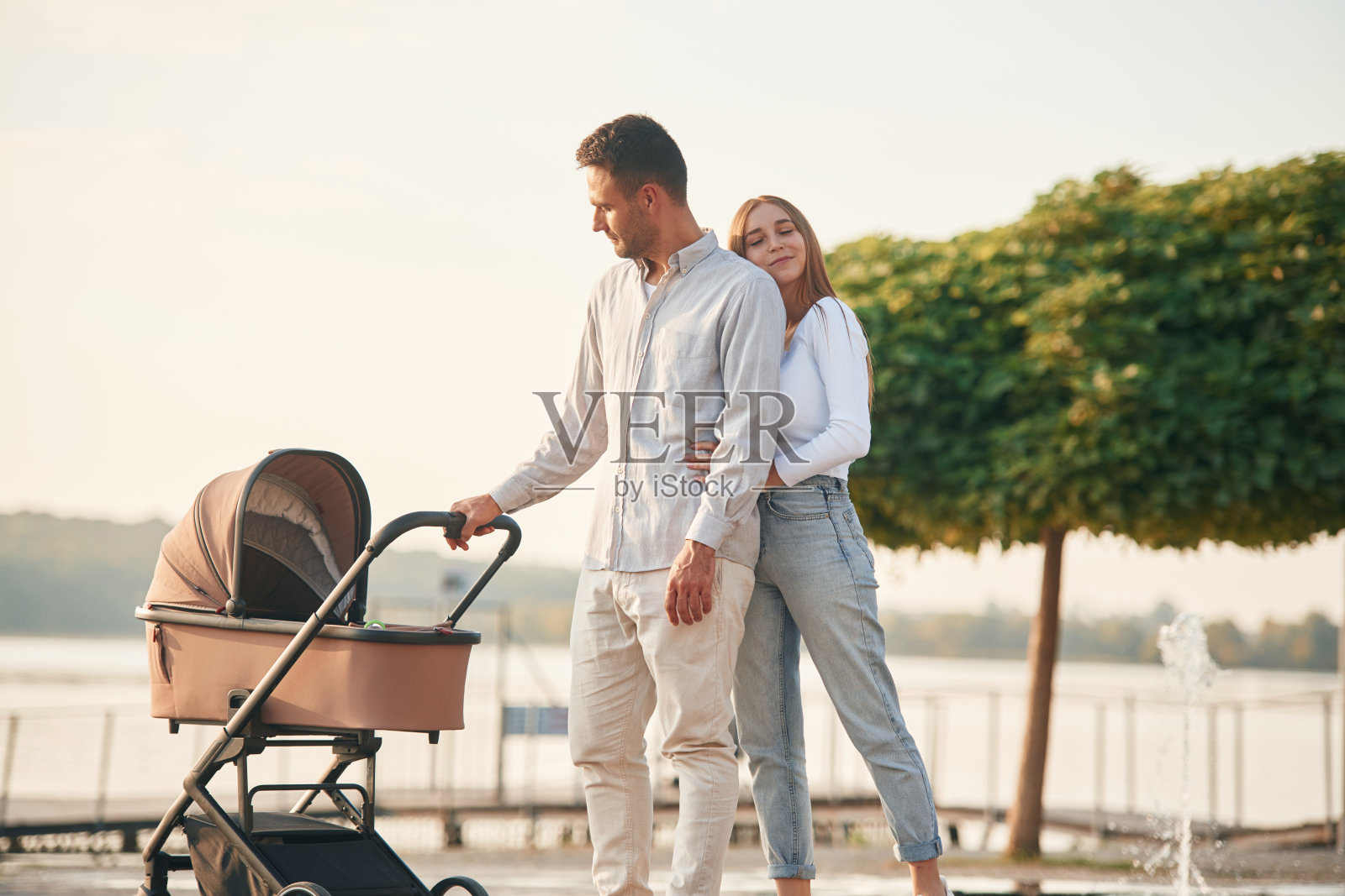 一对年轻夫妇推着婴儿车走在一起照片摄影图片