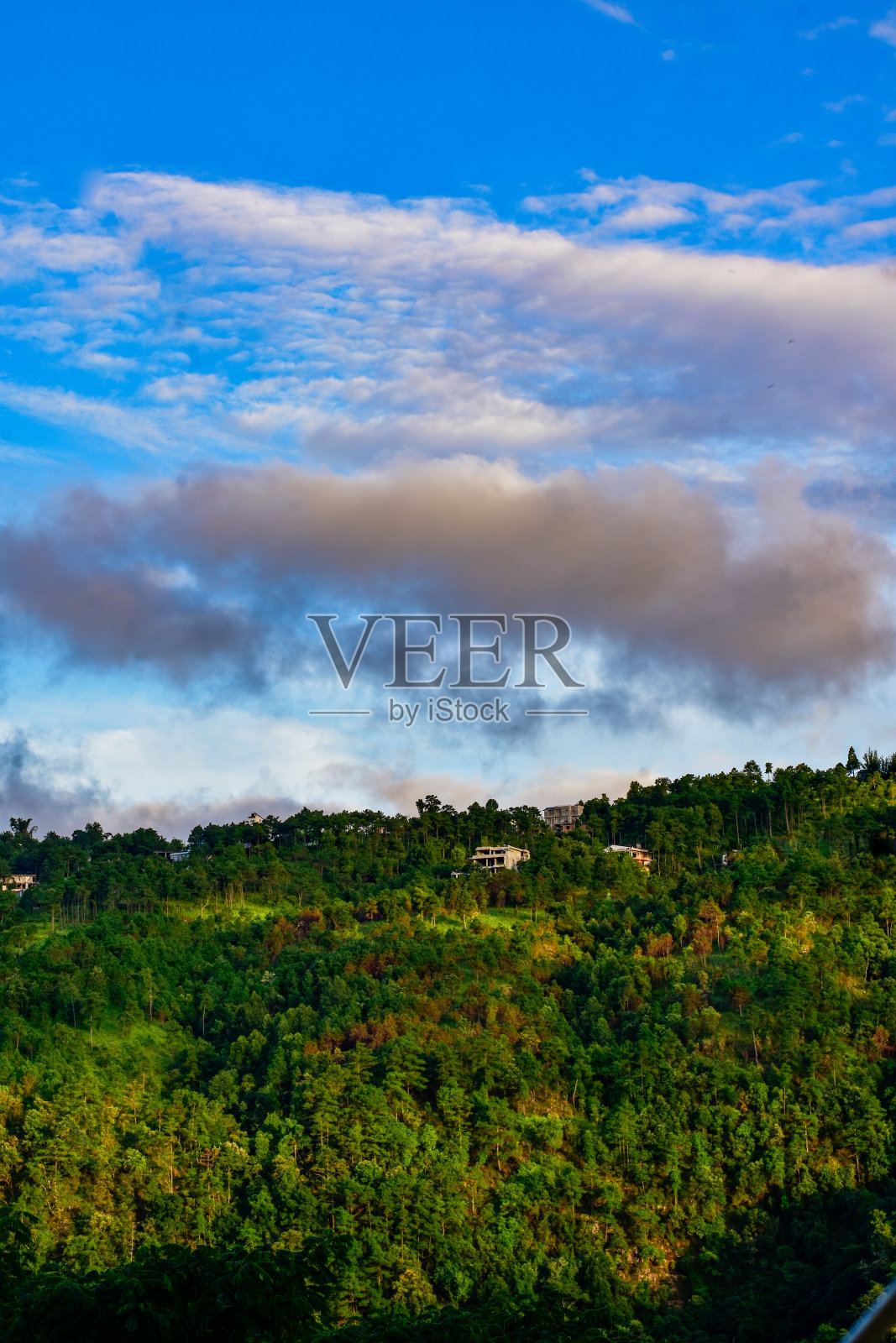 云彩笼罩着一座山和一座房子。照片摄影图片