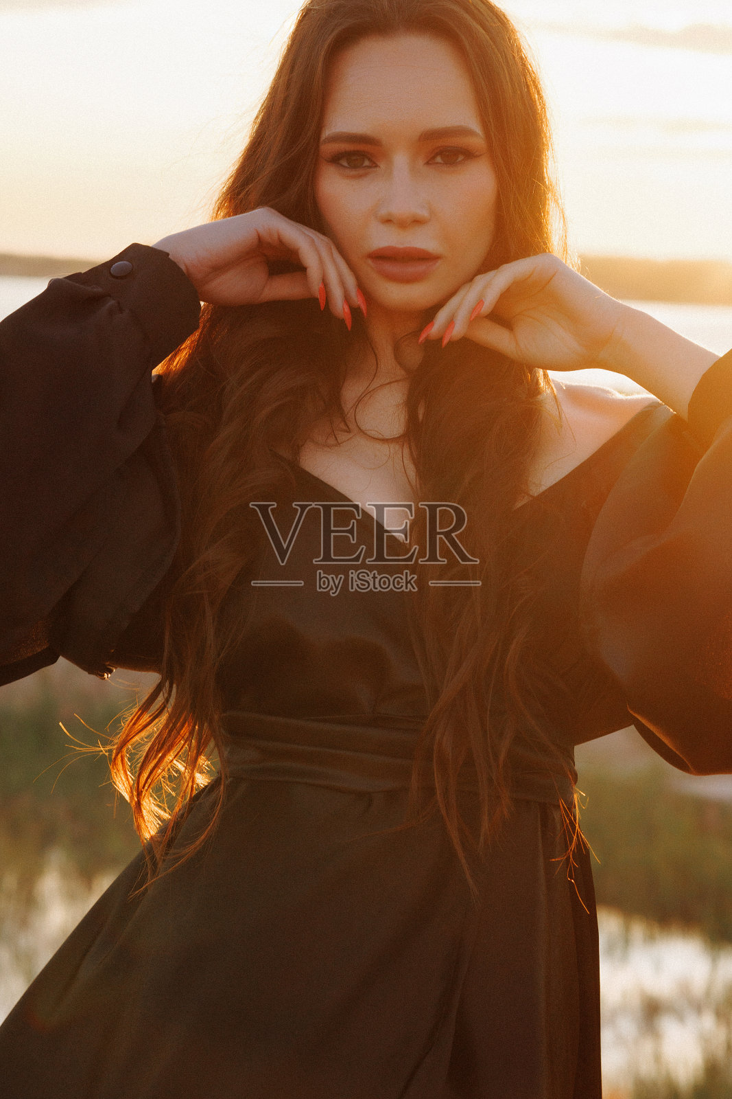 一个美丽的黑发女人的肖像，在日落时分穿着长发照片摄影图片