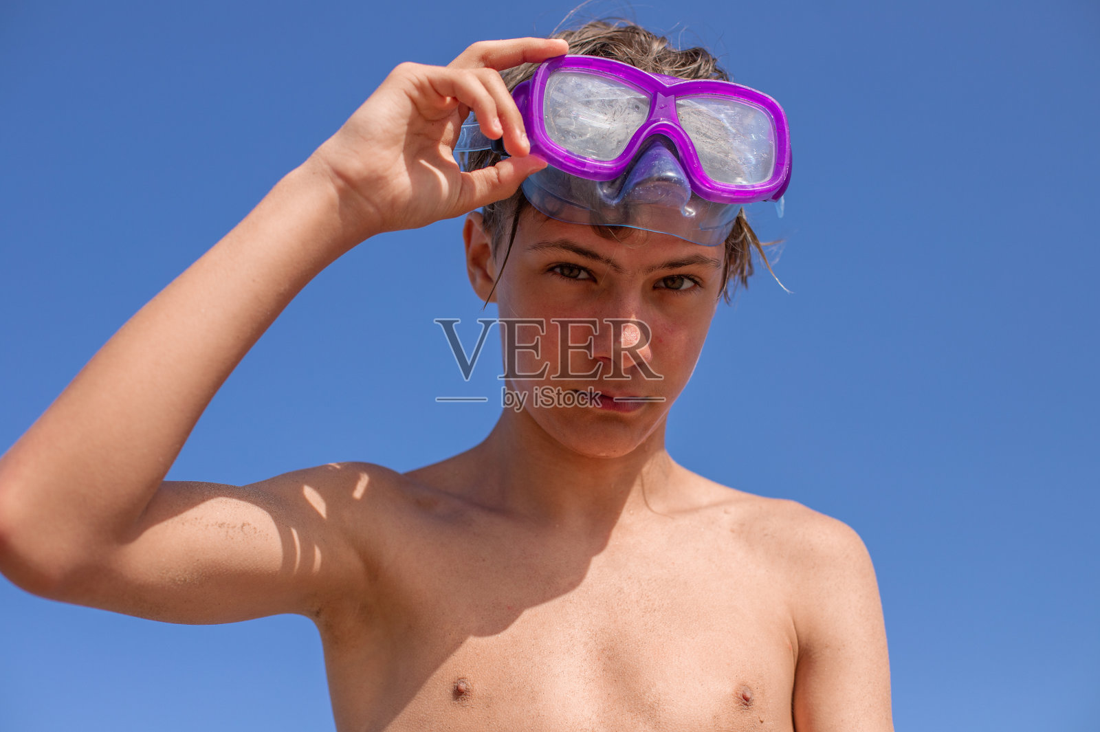 快乐的夏天:帅气的少年戴着潜水面罩，在充满活力的夏日沙滩上享受阳光和海风。照片摄影图片