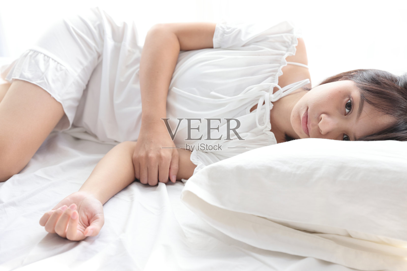 美丽的年轻女子腿睡在白色的卧室里照片摄影图片