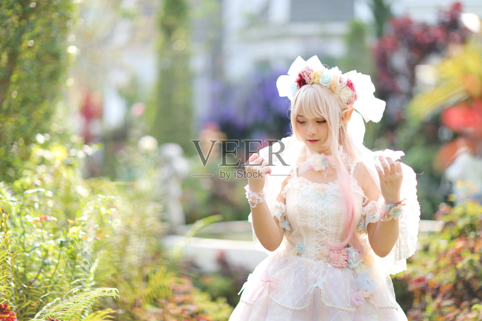 美丽的年轻女子穿着白色的洛丽塔连衣裙，带着日本花园的花朵照片摄影图片