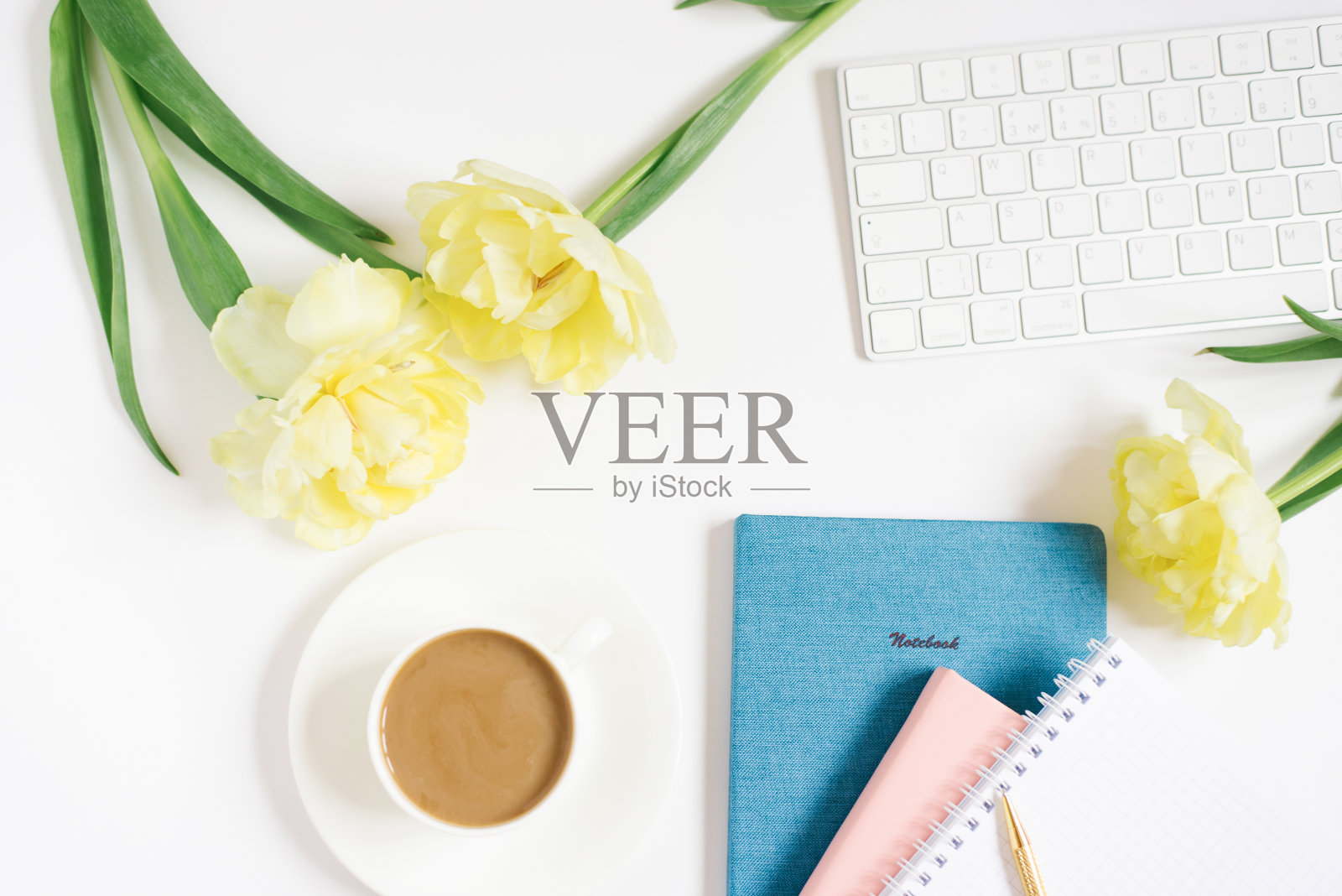 女性博主或自由职业者的工作场所。各种各样的笔记本，一支金笔，一杯带甜甜圈的咖啡，郁金香花。休息时间照片摄影图片