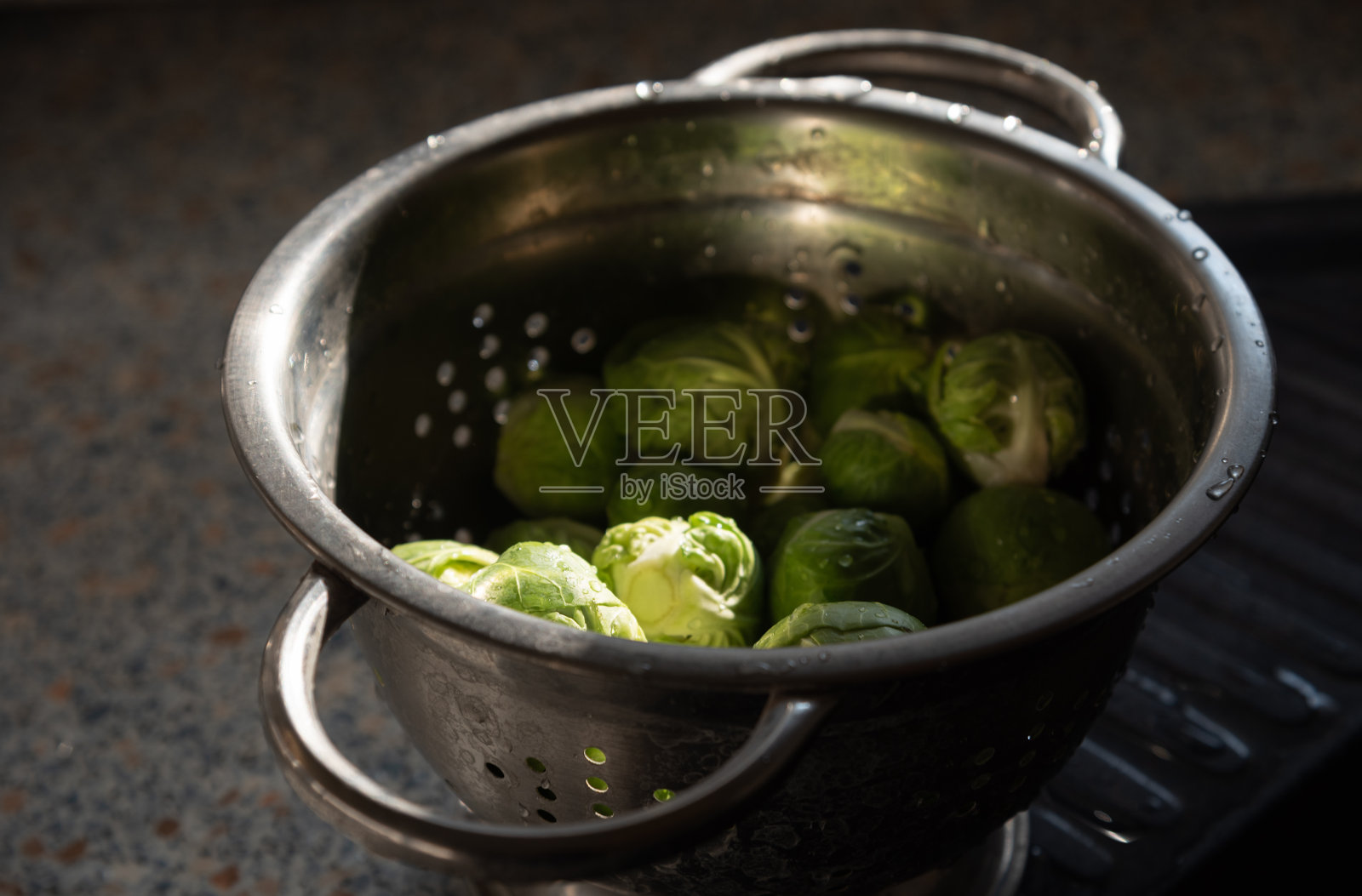 新鲜、干净、未煮熟的绿色抱子甘蓝，放入金属滤锅中。照片摄影图片