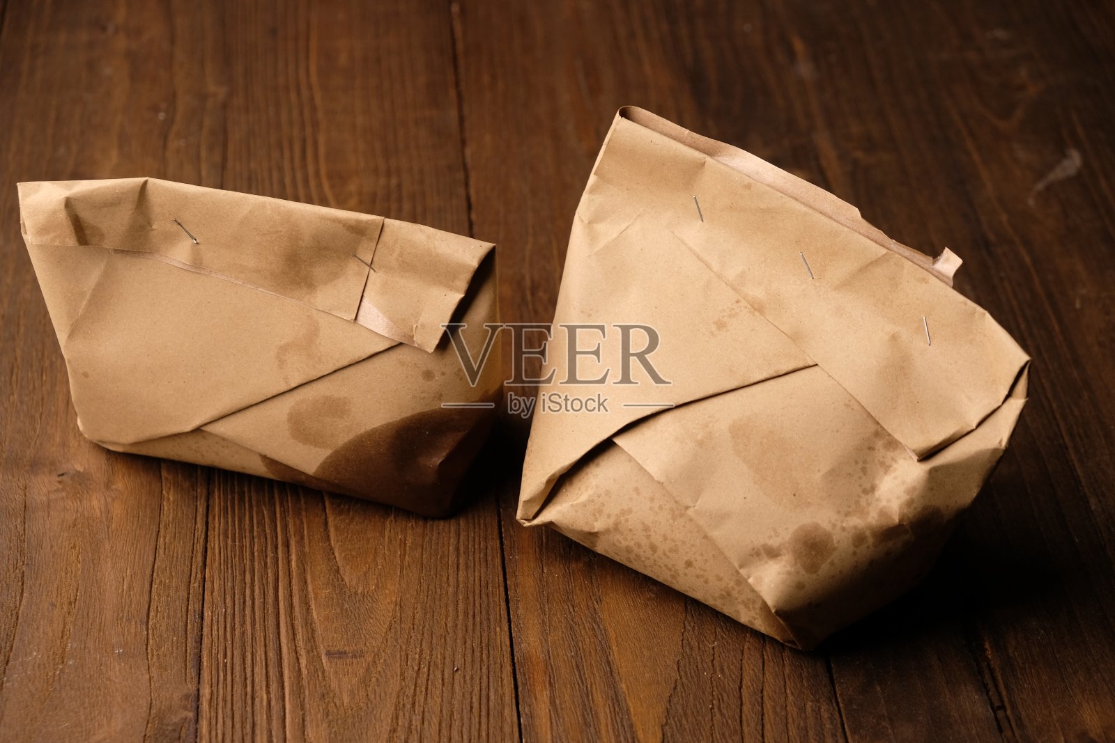 棕色木桌上放着两张米包装纸。印尼的食物。包装的大米。猫饭。angkringan Jogja。照片摄影图片