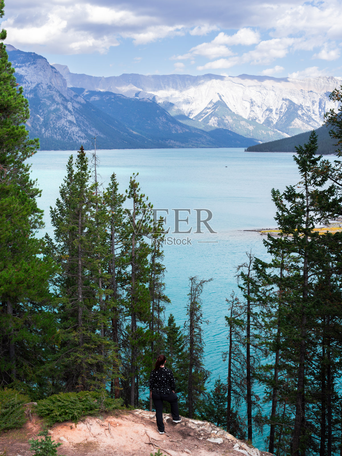 一个女人站在悬崖边上，望着一个大湖和山脉照片摄影图片