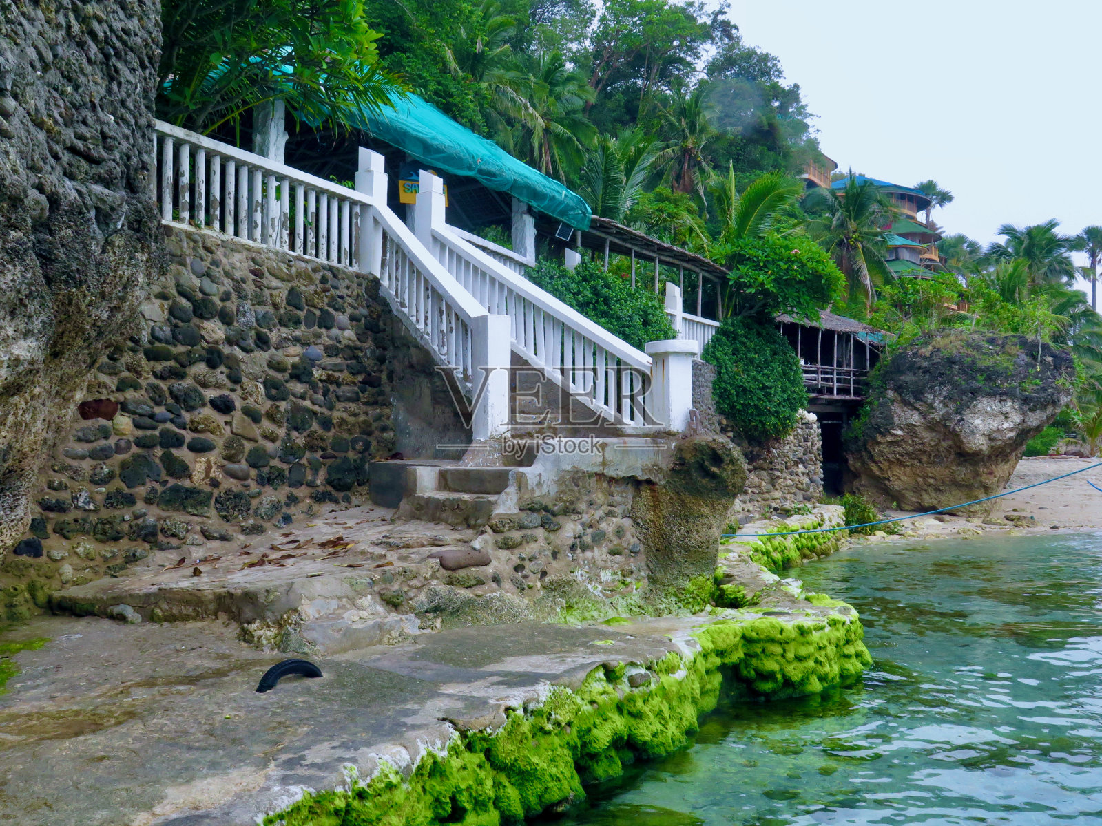 一段带栏杆的石阶通向水边。照片摄影图片