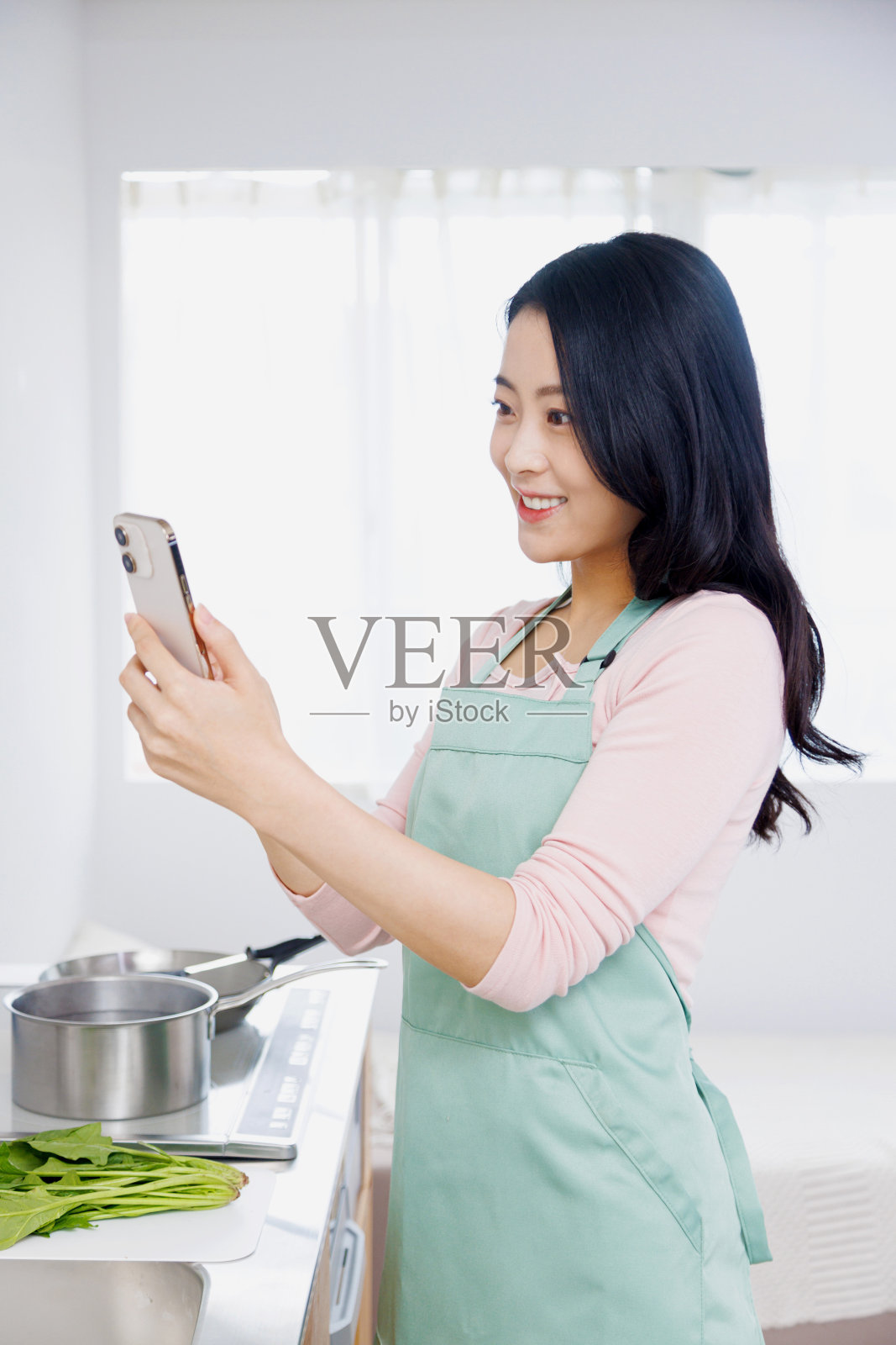 亚洲妇女在厨房用手机照片摄影图片