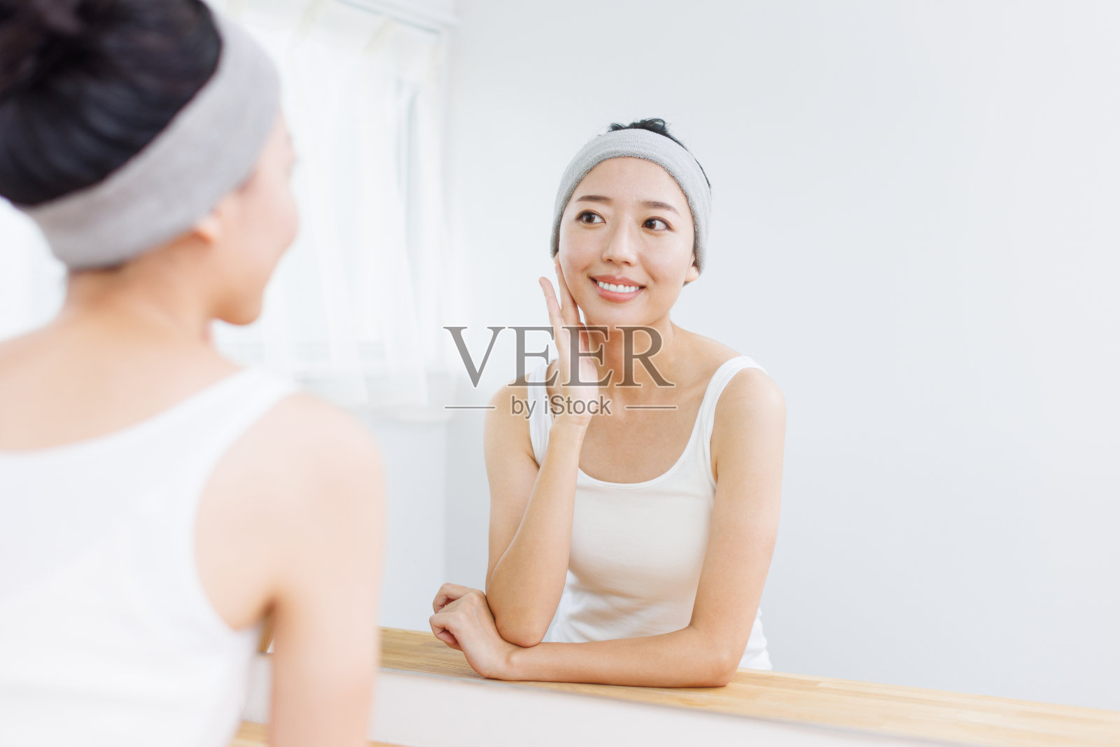 年轻的亚洲女人抚摸着她的脸照片摄影图片