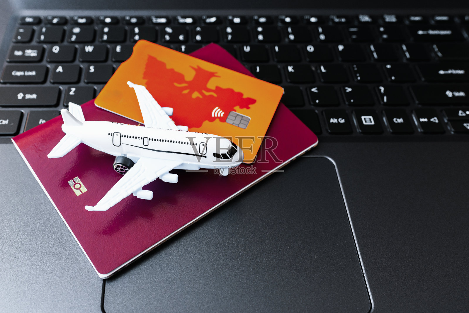 旅行准备概念。玩具飞机，信用卡，护照和笔记本电脑键盘，特写。照片摄影图片