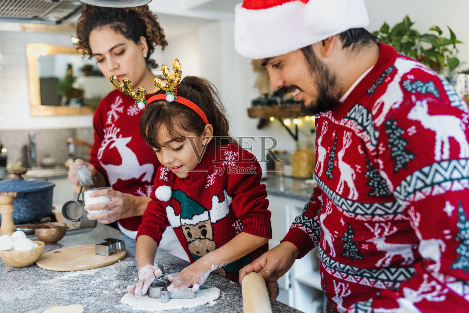 拉丁美洲墨西哥的拉丁家庭父母，母亲，父亲和女儿在家中烘烤圣诞饼干照片摄影图片