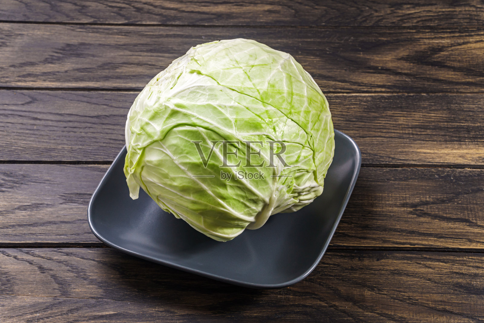 整个生卷心菜放在木桌上的盘子里照片摄影图片