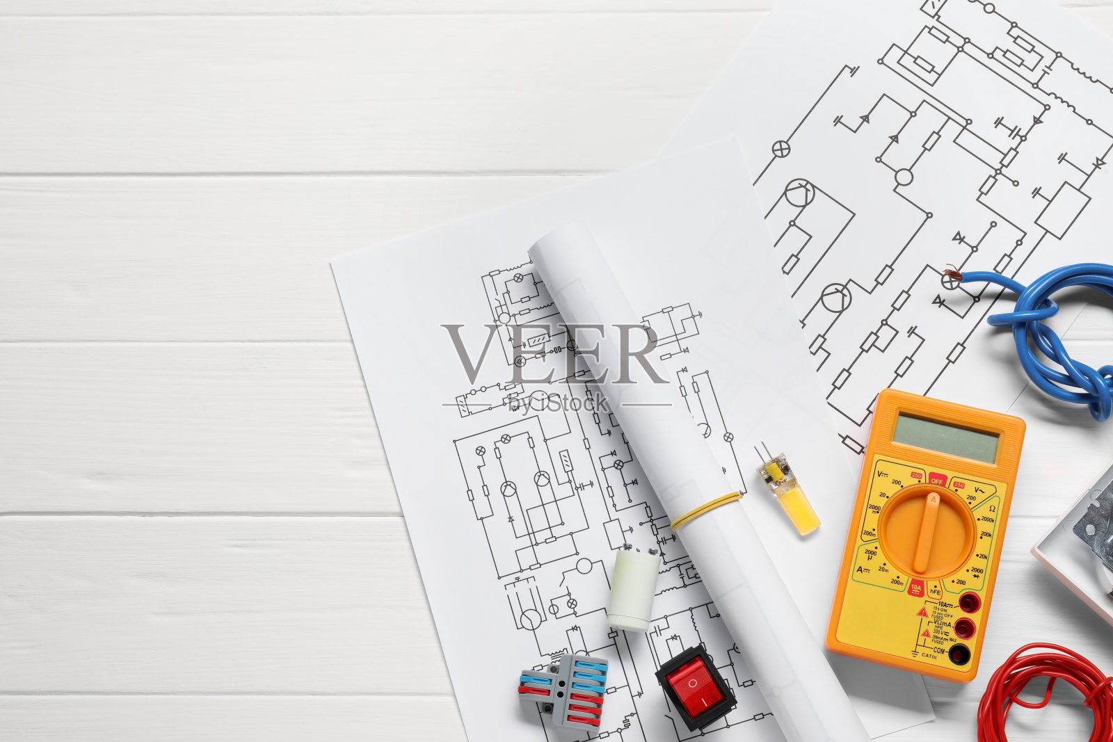 白色木桌上平铺着接线图和数字万用表，留出文字空间照片摄影图片