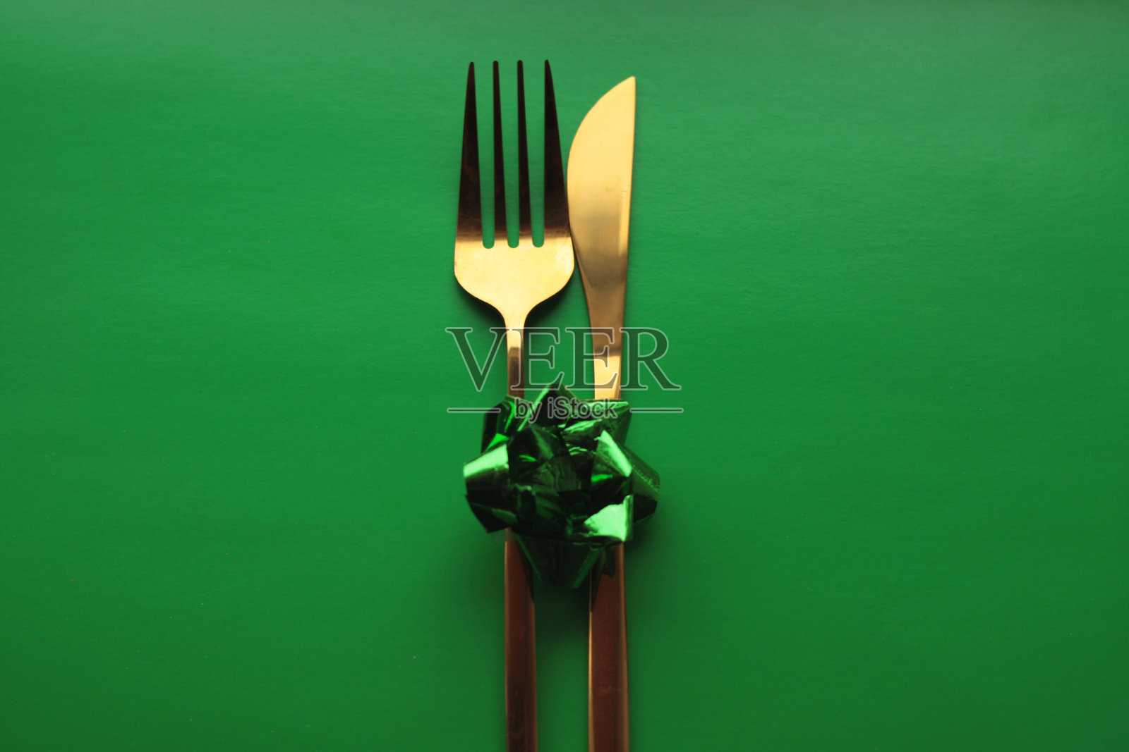 金色餐具，绿色背景上有一个绿色的蝴蝶结照片摄影图片