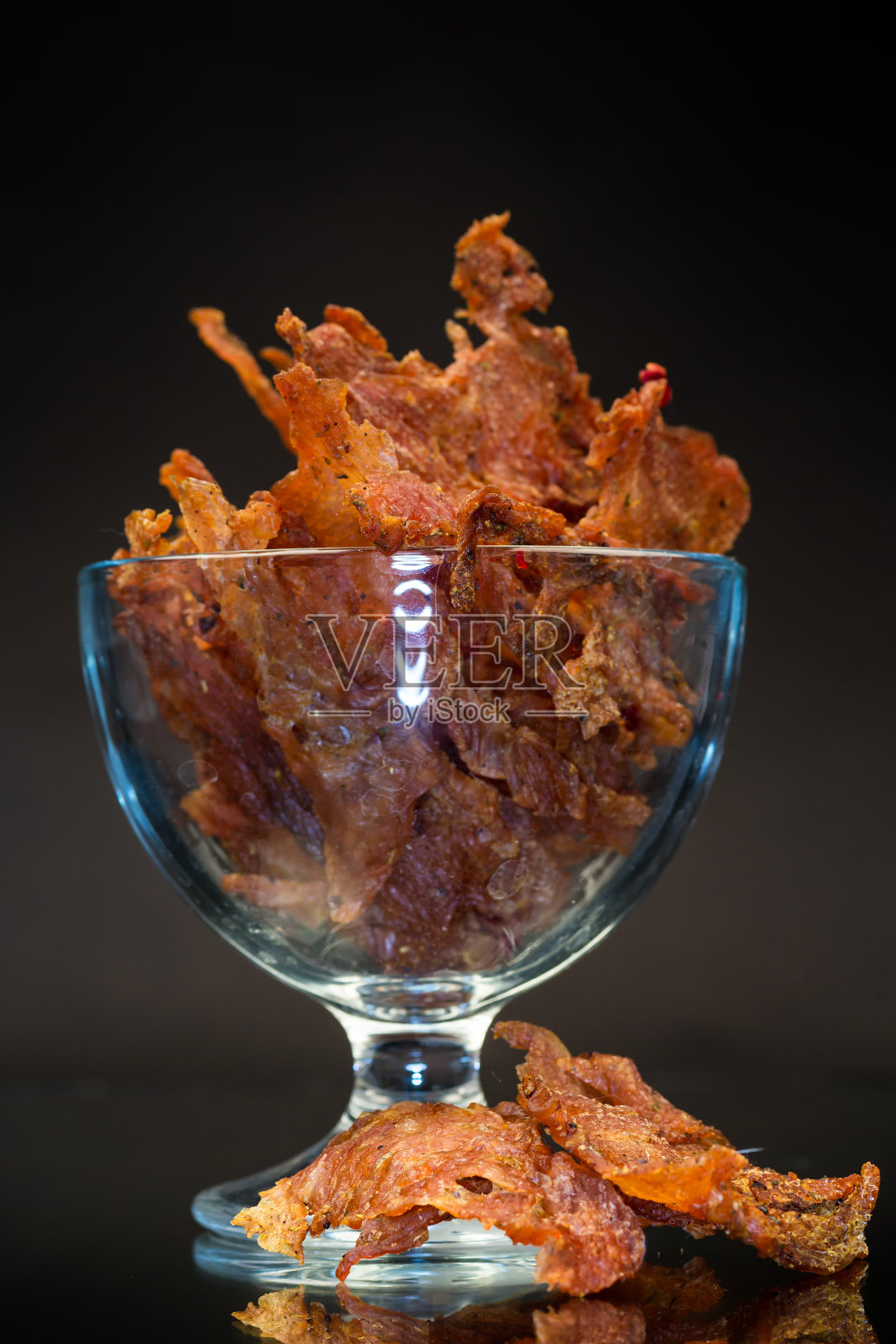干肉与香料在一个玻璃碗，孤立的黑色背景照片摄影图片