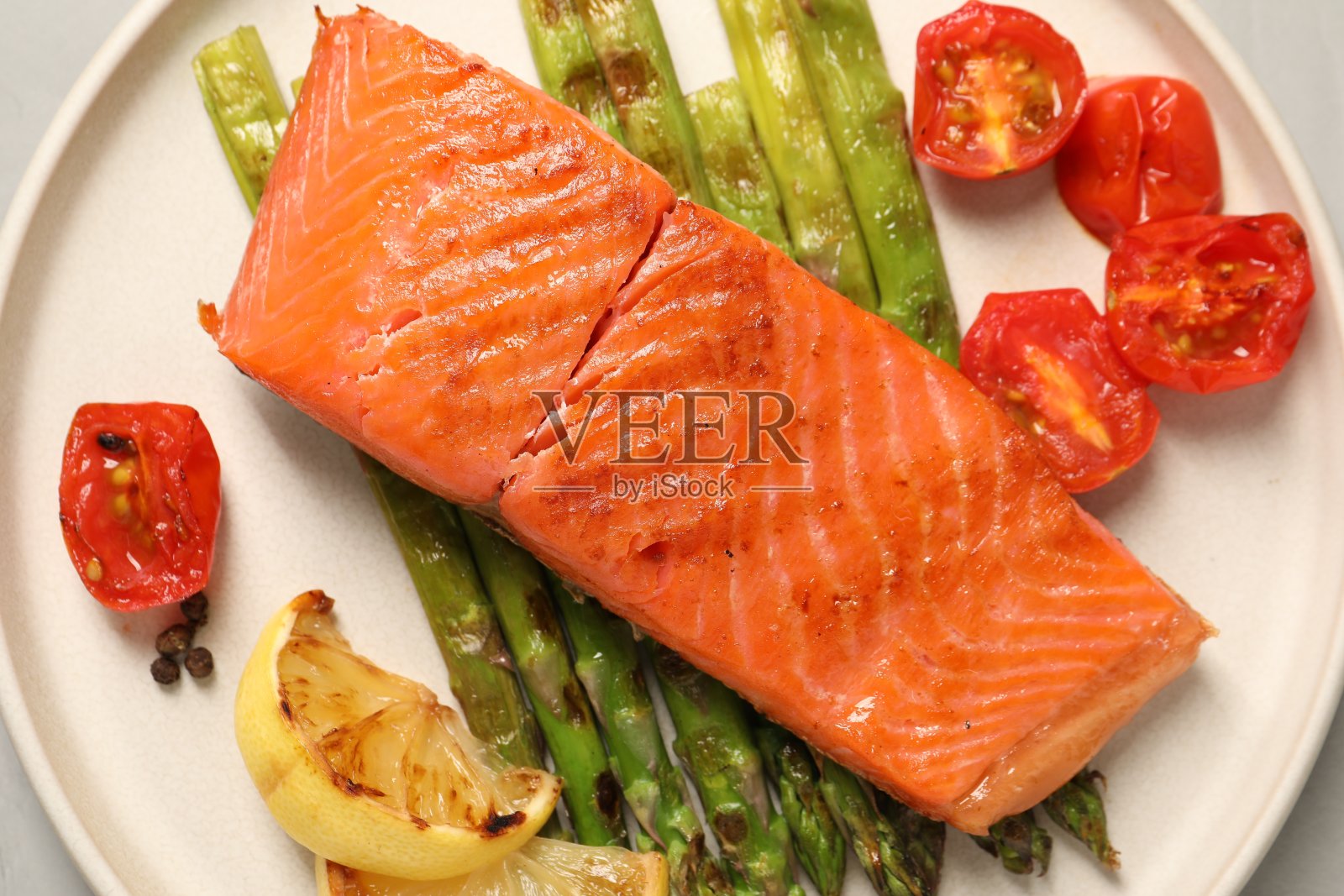 美味的烤鲑鱼配芦笋，西红柿，香料和柠檬，在浅色的桌子上，俯视图照片摄影图片