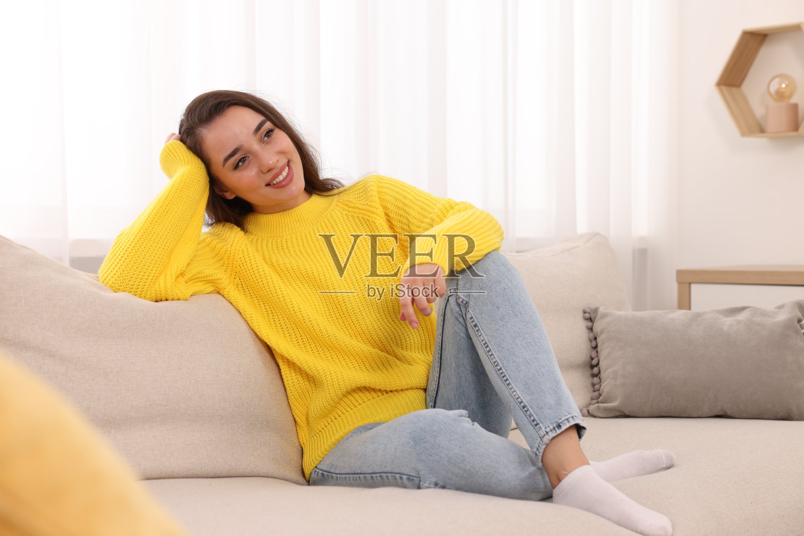 漂亮的年轻女子穿着时尚温暖的毛衣躺在家里的沙发上照片摄影图片