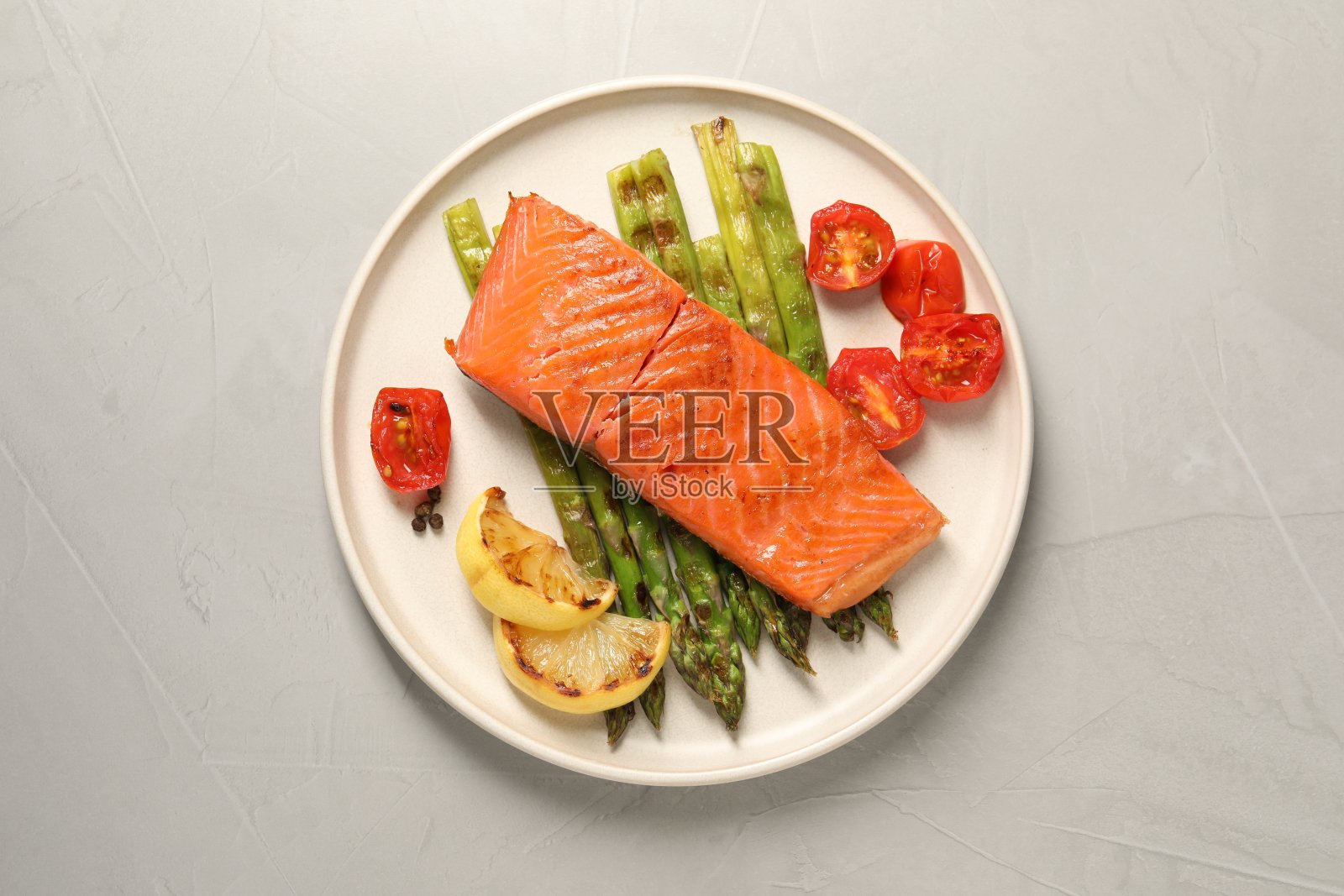 美味的烤鲑鱼配芦笋，西红柿，香料和柠檬，浅灰色的餐桌，俯视图照片摄影图片