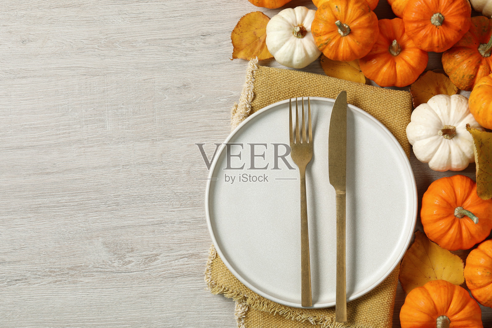 感恩节快乐。漂亮的餐桌布景，秋天的树叶和南瓜在木制的背景上，平铺着文字的空间照片摄影图片