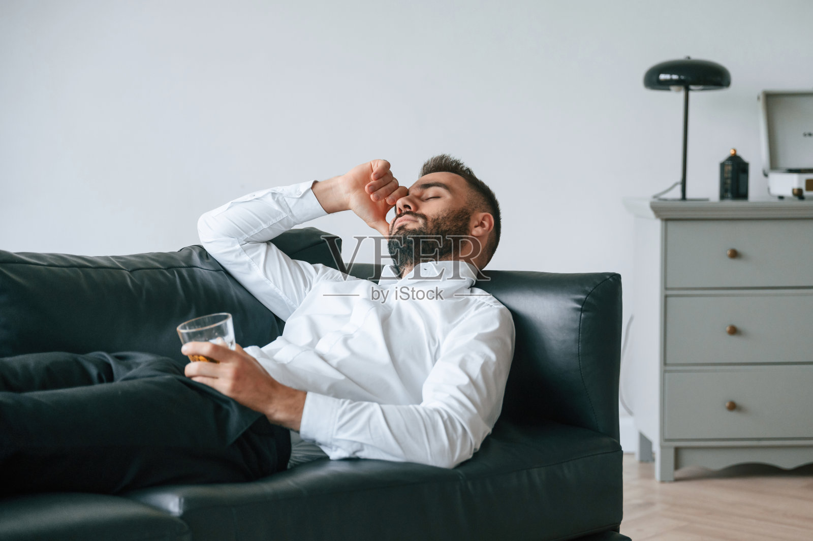 头痛，躺在沙发上。沮丧的年轻男子在室内喝酒照片摄影图片