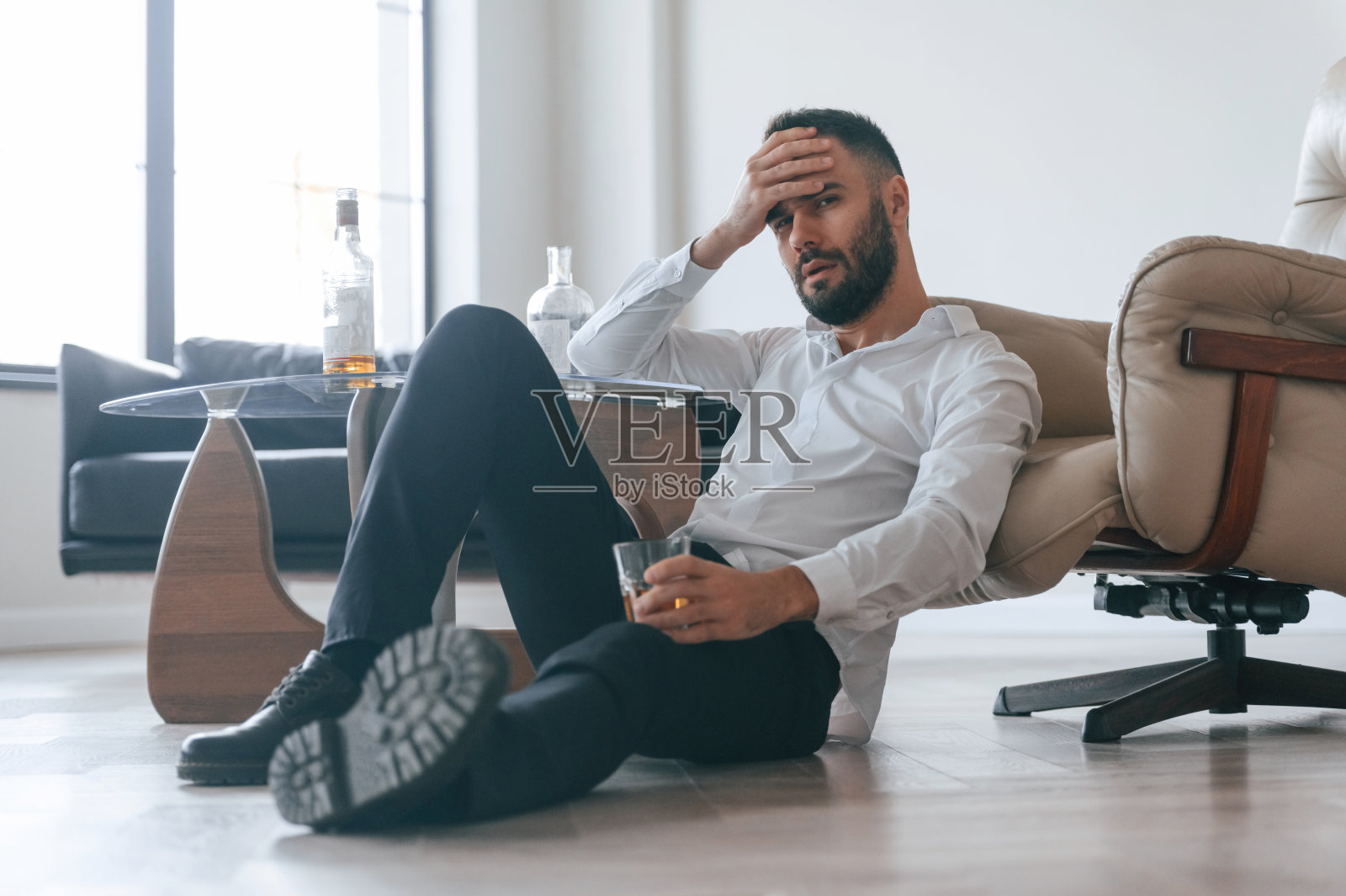 坐在地上，悲伤的酗酒男子照片摄影图片