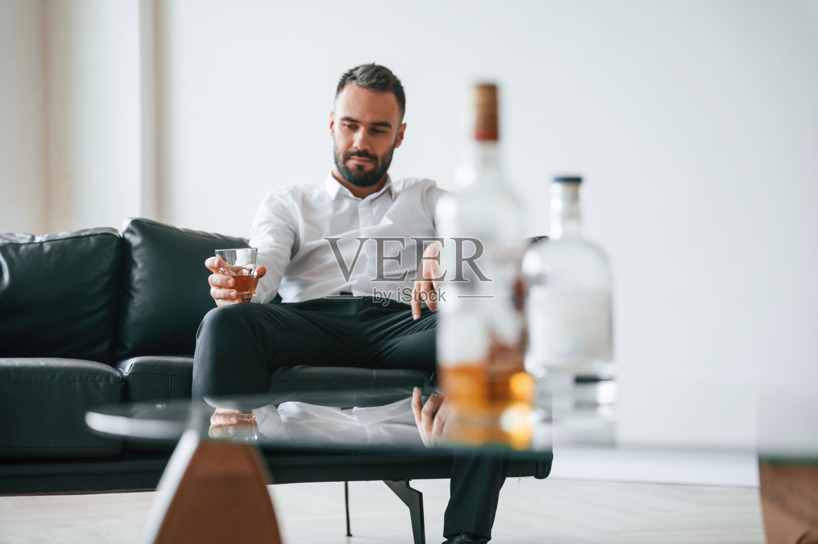 穿着正装。生意上的失败。心烦意乱的年轻酒徒在室内照片摄影图片