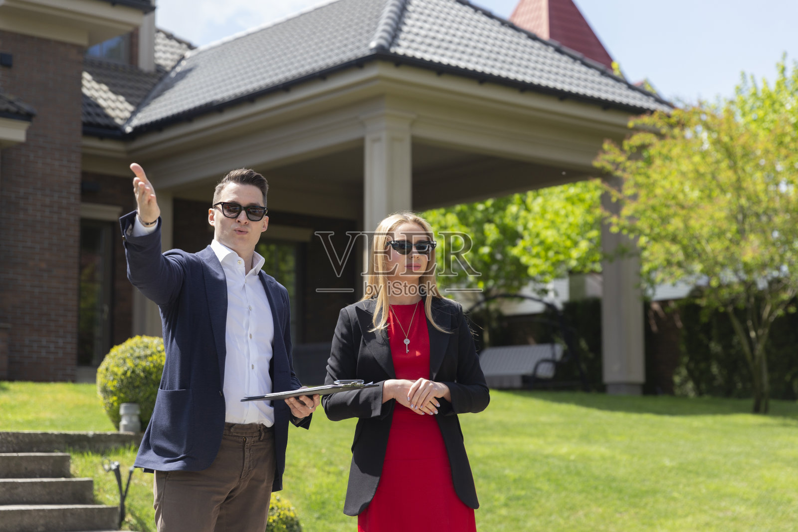 金发女商人在房地产经纪人的帮助下检查住所照片摄影图片