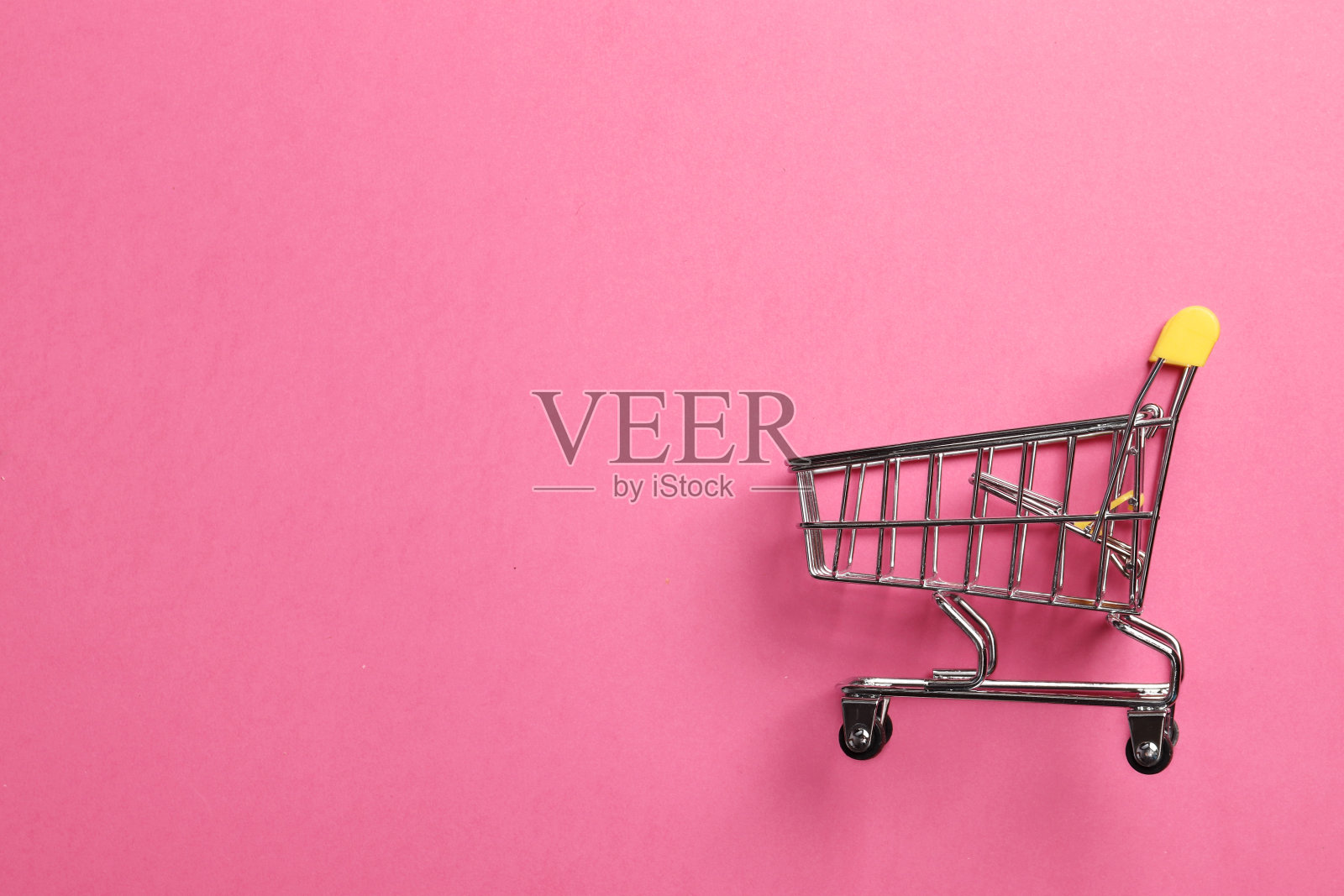购物车在粉红色的背景与空间的文字。照片摄影图片
