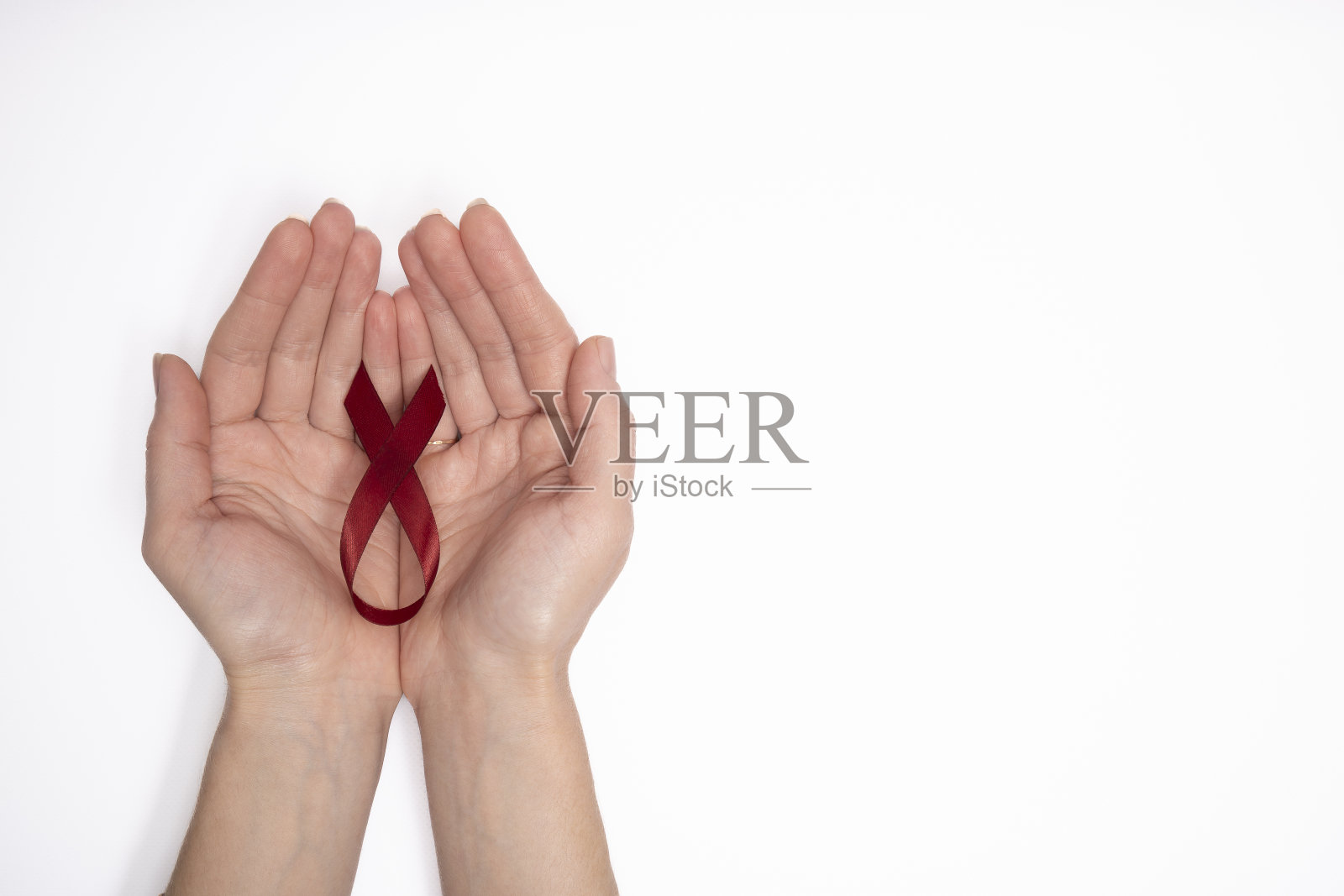 妇女手持红丝带作为世界癌症日的象征，白底上是乳腺癌意识的标志。照片摄影图片
