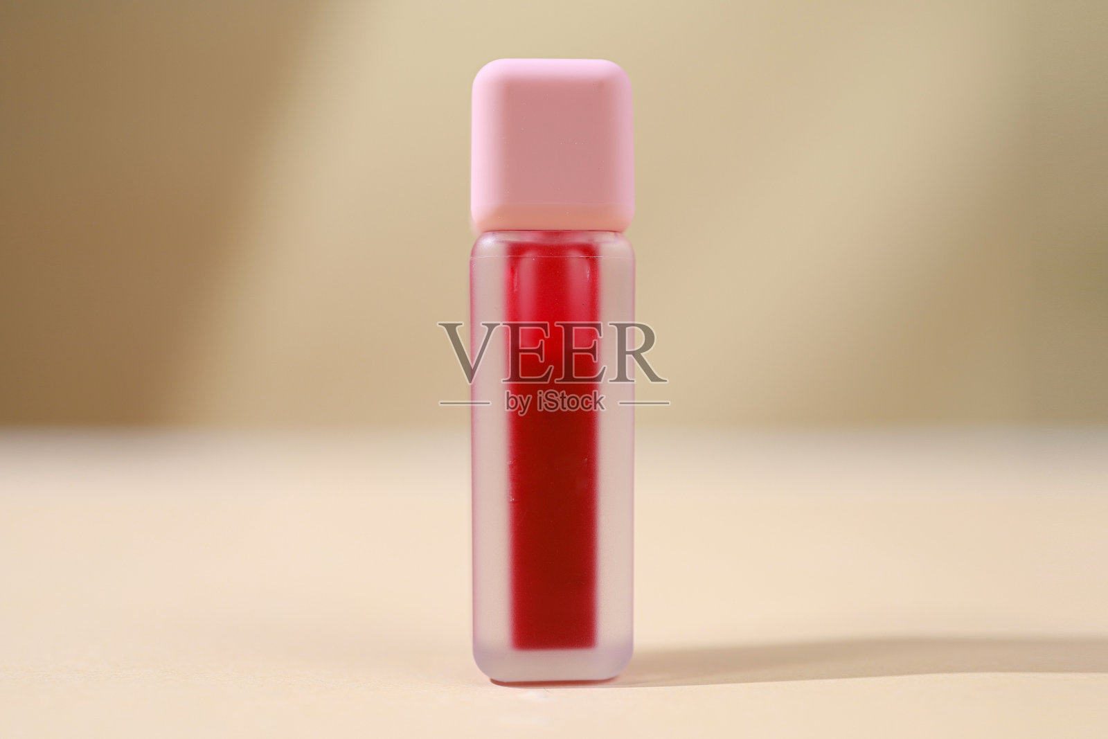 液体唇膏，唇彩，优雅的玻璃瓶，粉红色的盖子。当季流行色。唇彩的纹理孤立在白色的背景。装饰化妆品的包装模型。照片摄影图片