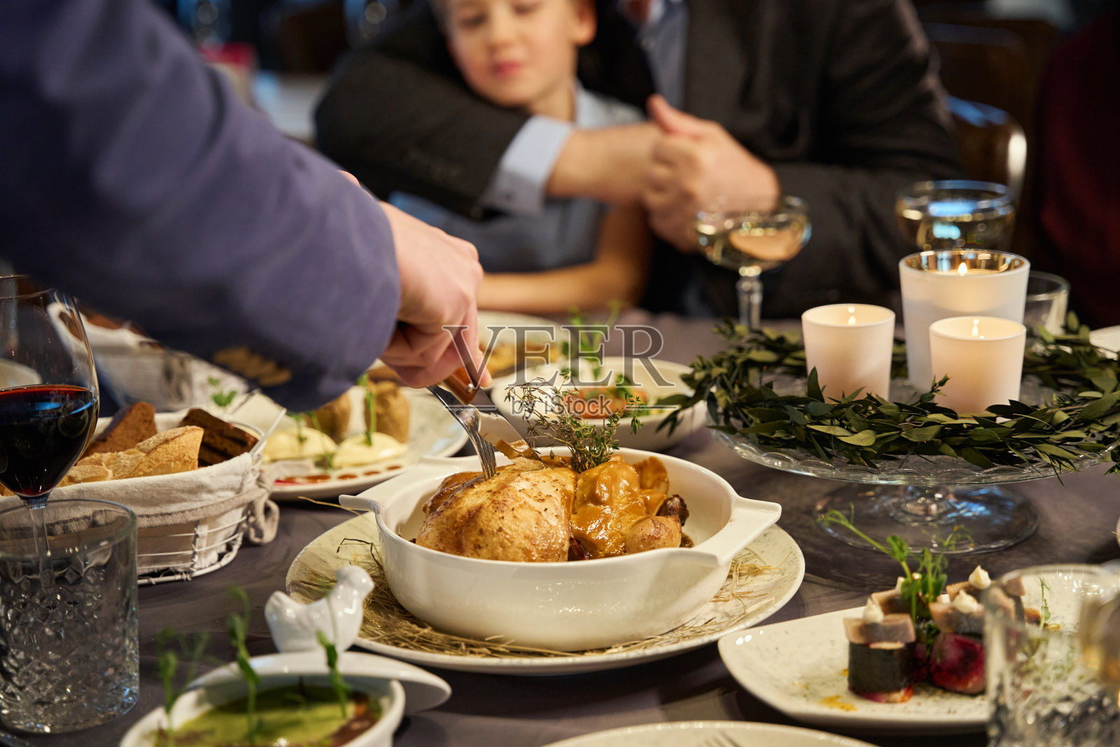 在与家人的节日晚餐上切烤火鸡的人面目全非照片摄影图片