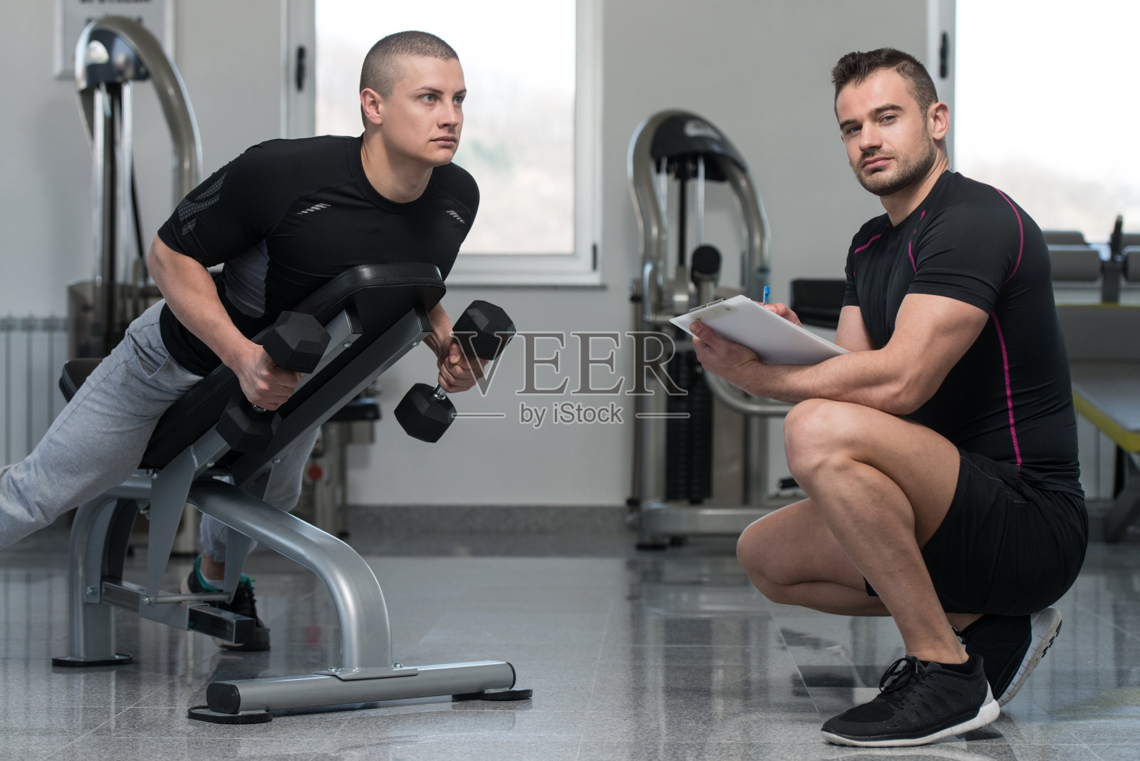 教练写在剪贴板上，而男子训练回来照片摄影图片