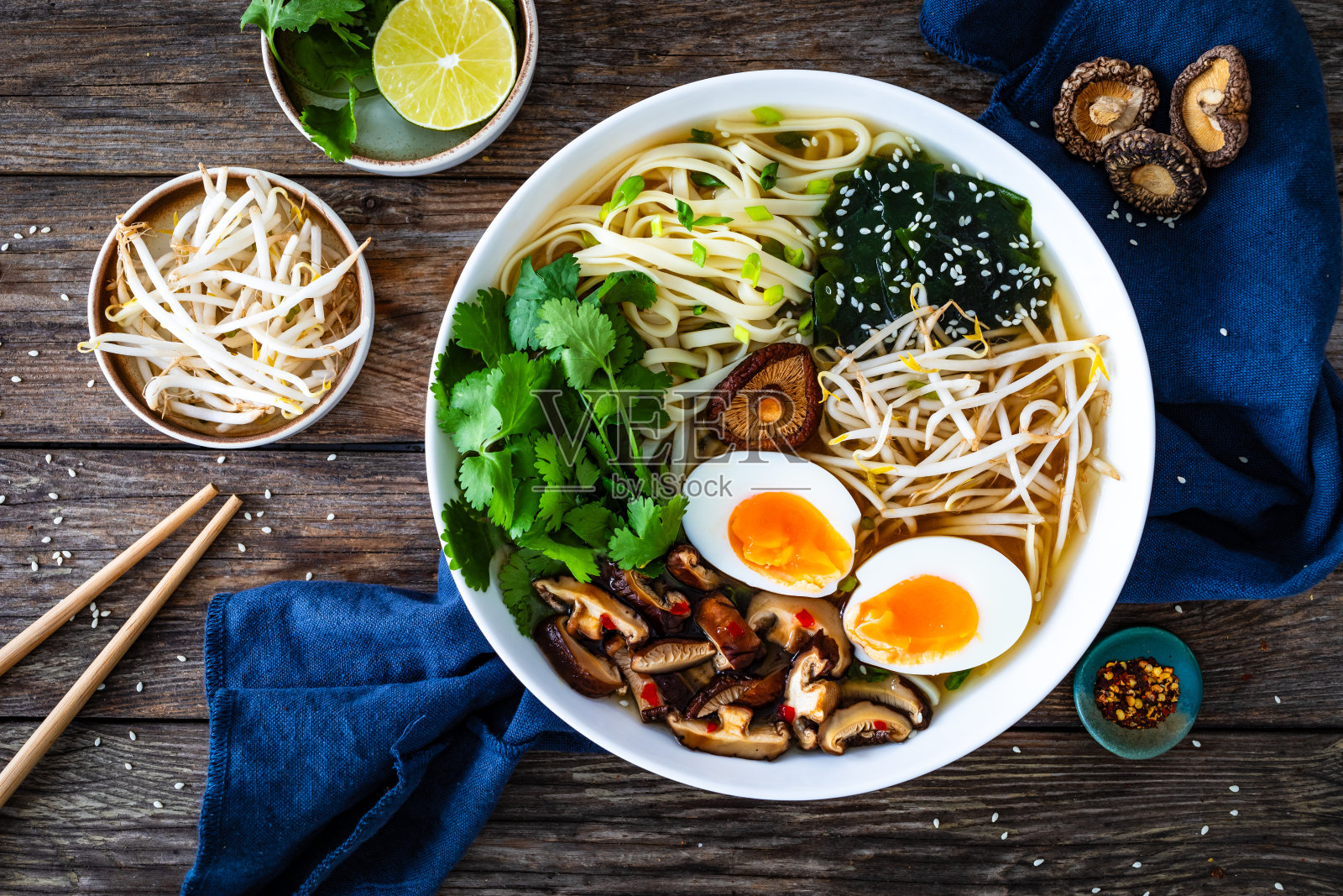 亚洲风格的汤。木桌上有炒面、煮鸡蛋、香菇、香菜和绿芽的肉汤照片摄影图片