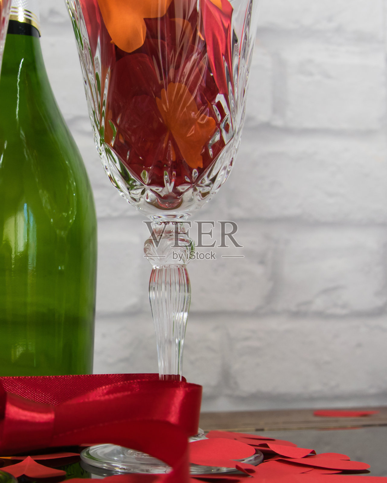 纸上的红心，红带子上的两杯香槟酒，酒瓶上的石头背景。照片摄影图片