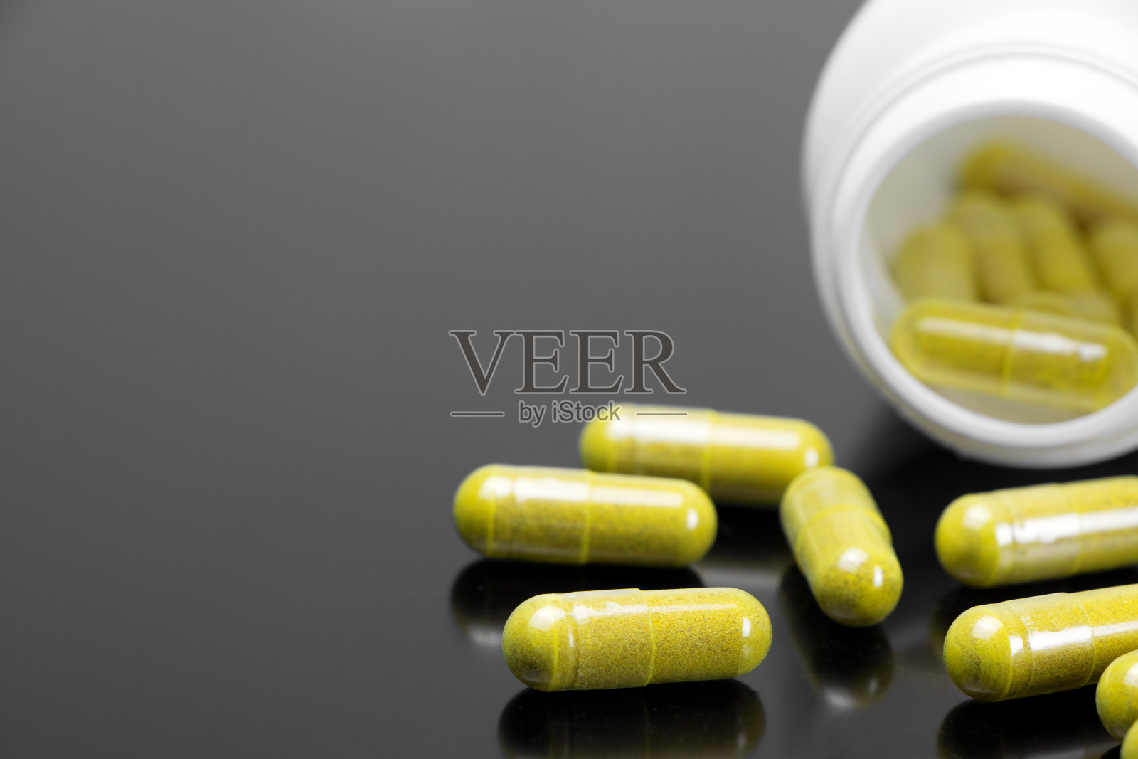 黄色的胶囊和黑色的背景。在黑暗的背景上散落着药片。副本的空间。医药保健照片摄影图片