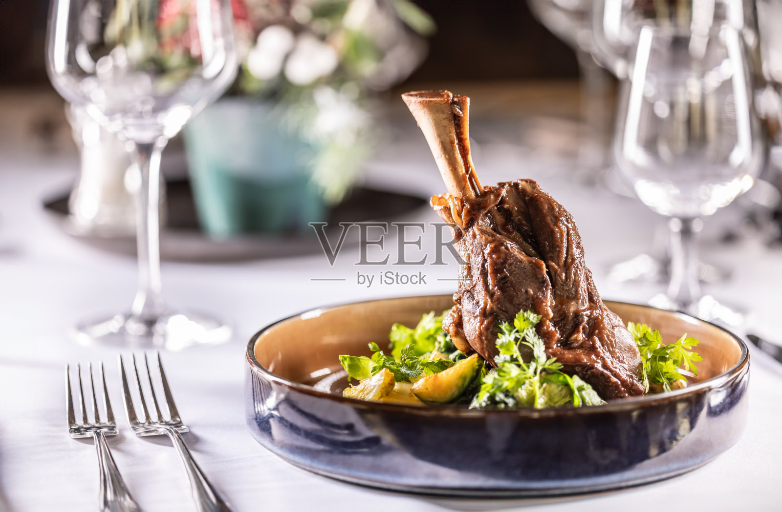 在酒店的餐厅里，羊腿配土豆泥配奶油羽衣甘蓝、酱汁和香草。照片摄影图片