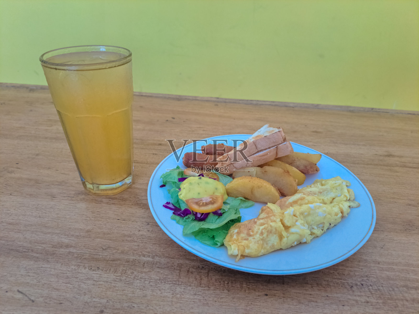 新鲜沙拉配生菜，煎蛋卷，吐司面包，土豆角，炸香肠，茄子片，番茄片，蛋黄酱和橙冰。食物和饮料菜单照片摄影图片