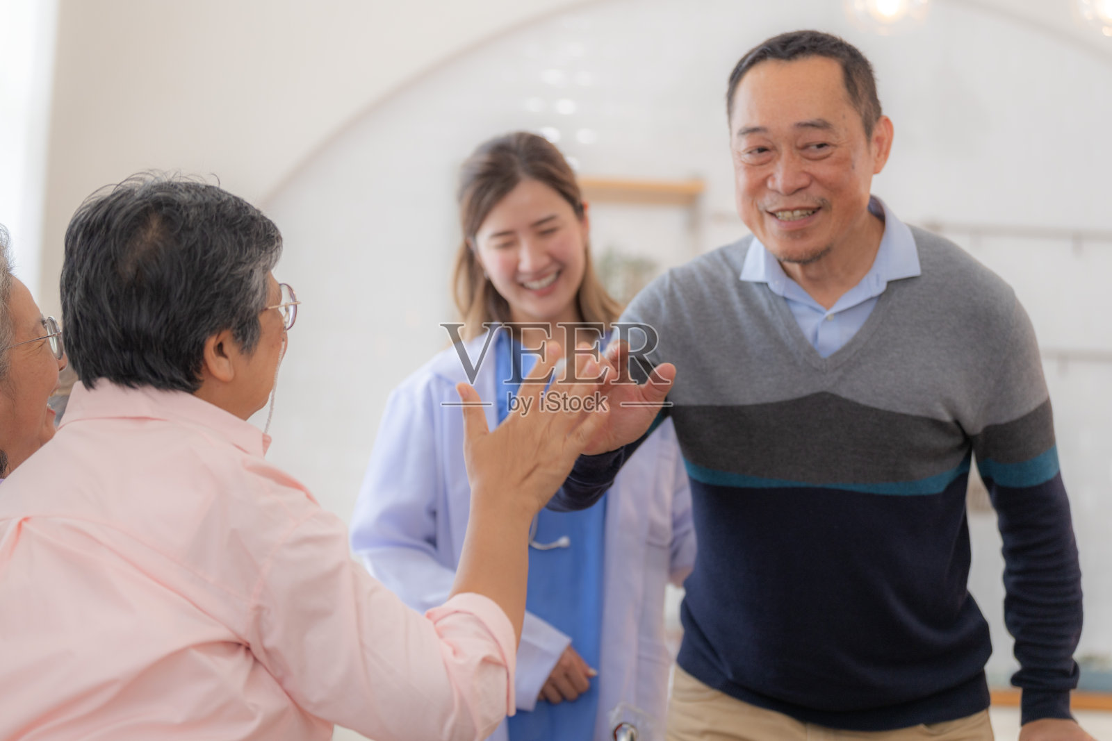 亚洲年轻护士支持老年男子用助行器行走。美丽的护士帮助和照顾。老年成熟的爷爷病人在医院和一群老年朋友一起做物理治疗。照片摄影图片