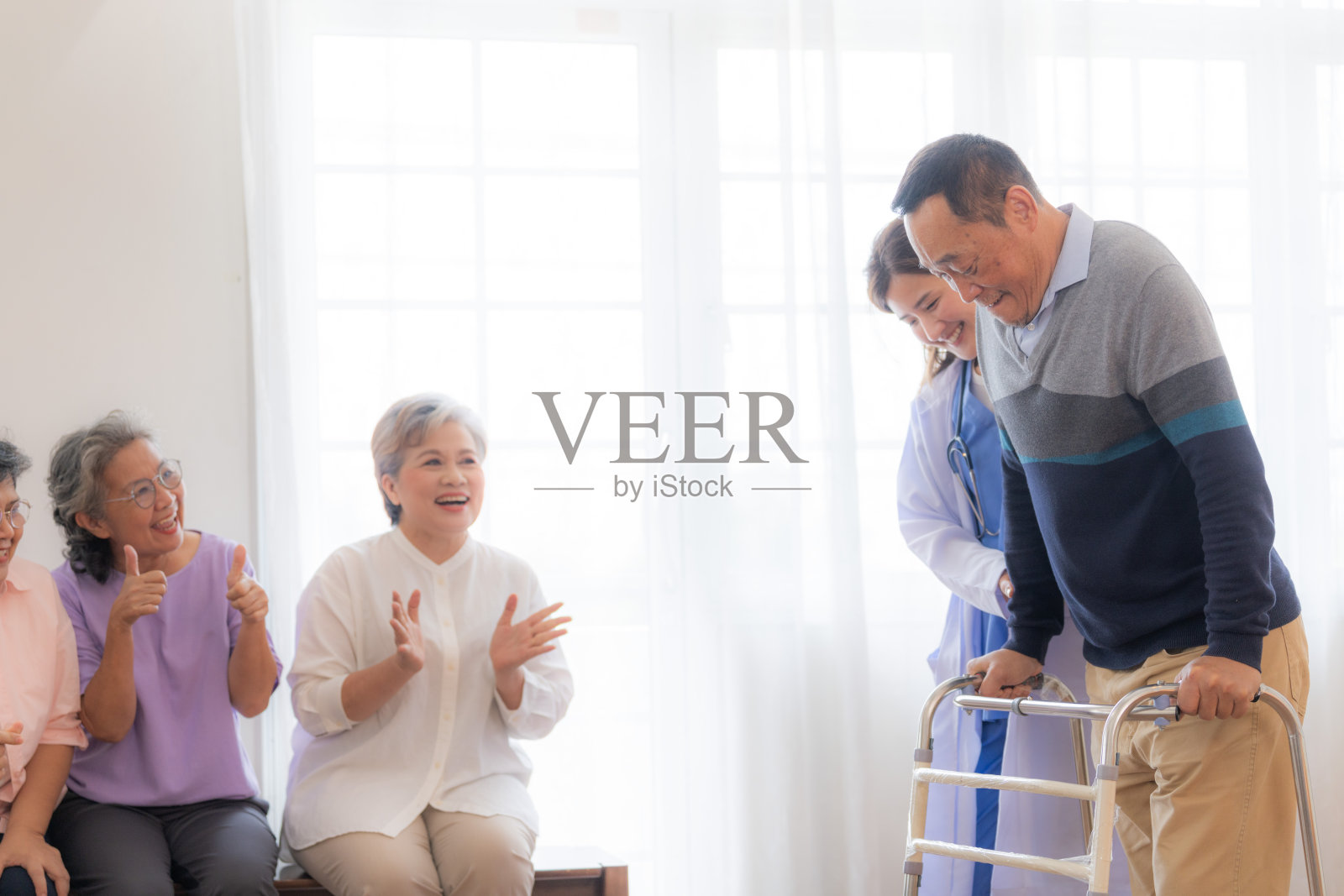 亚洲年轻护士支持老年男子用助行器行走。美丽的护士帮助和照顾。老年成熟的爷爷病人在医院和一群老年朋友一起做物理治疗。照片摄影图片