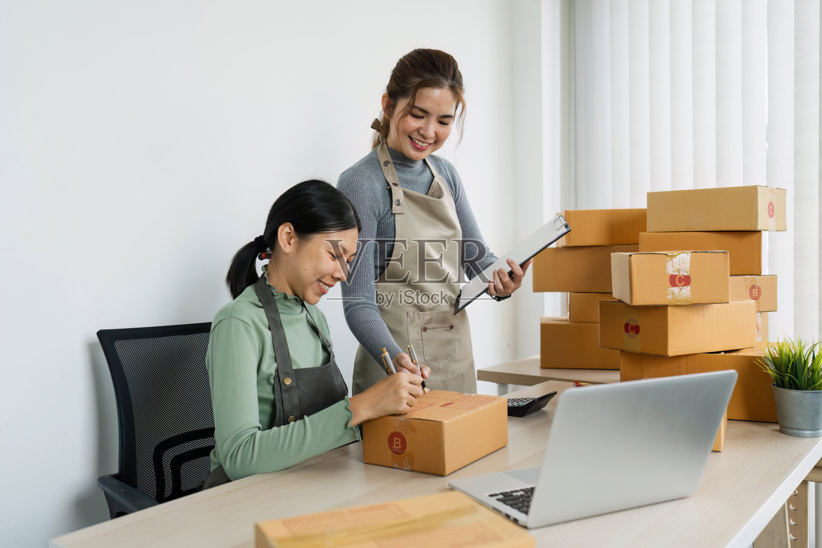 中小企业主在工作中使用笔记本电脑。用包裹纸盒投递给客户进行网上销售照片摄影图片