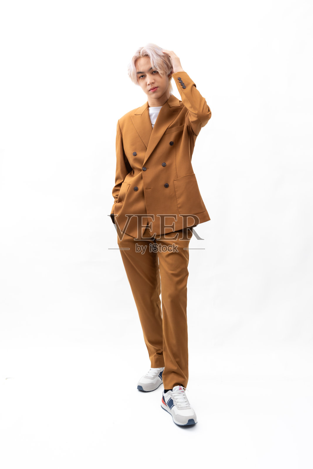 金棕色西装。亚洲年轻人的时尚肖像。模特、服装和化妆品。年轻的男模特金发时髦的衣服孤立在白色的背景照片摄影图片