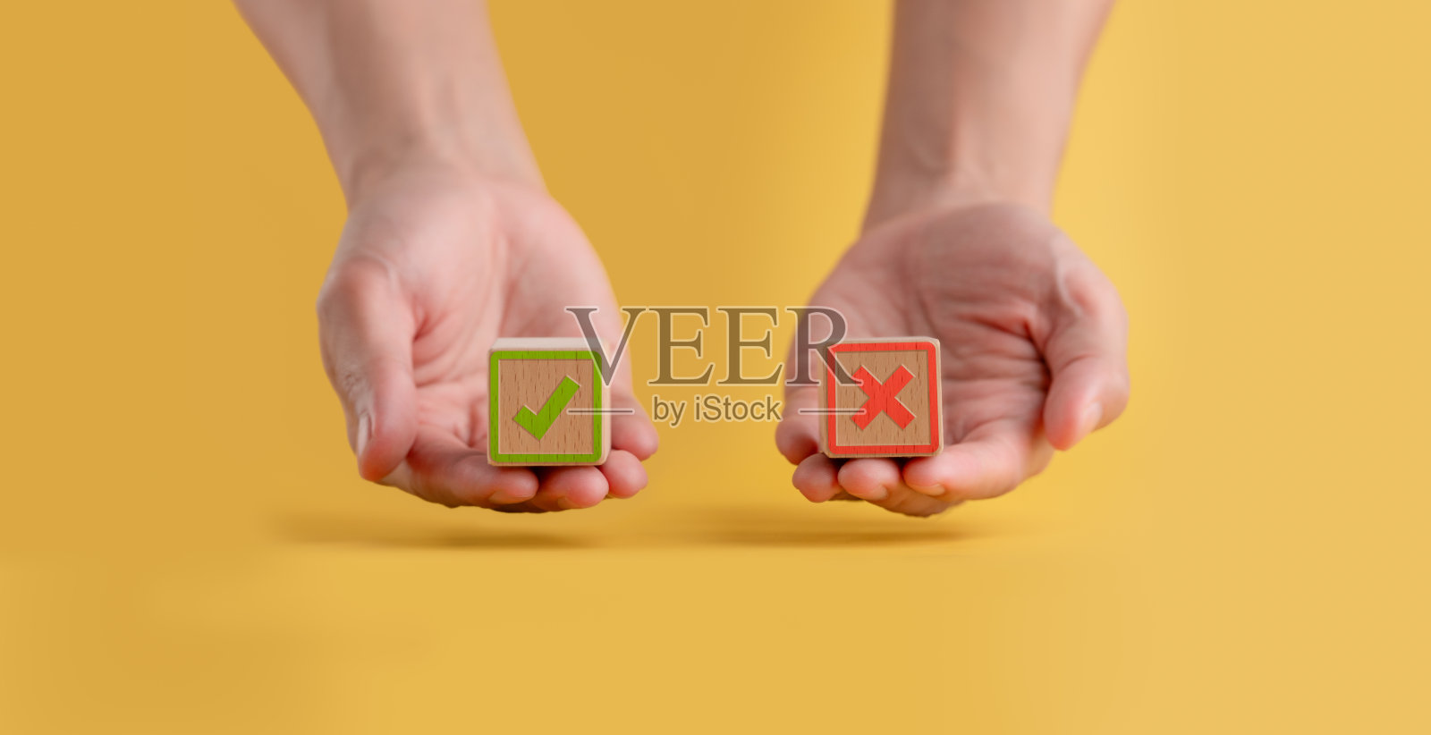 手里拿着一块木块，上面有一张纸，上面写着对与错、真与假、接受与拒绝、评价投票结果是或否、民意调查概念，黄色背景照片摄影图片