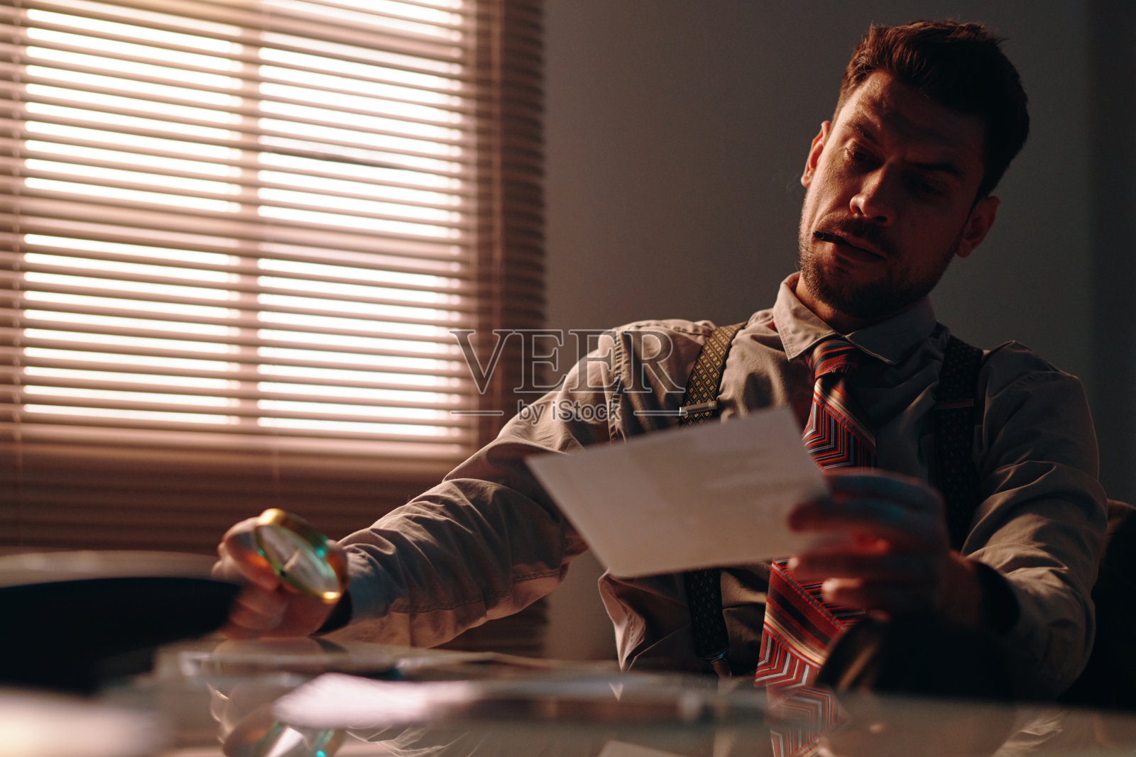 聚焦在一个年轻人坐在桌子前的相机和看照片照片摄影图片